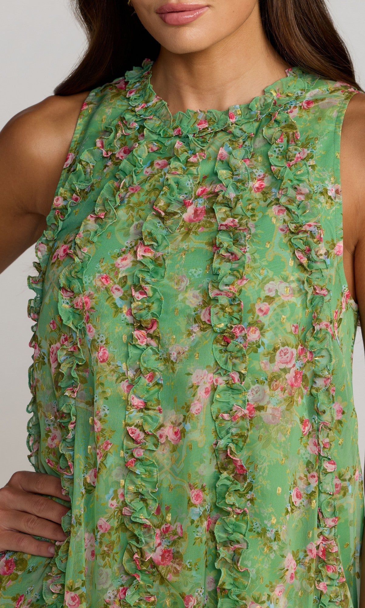 Woman modeling the Mac Duggal 8103 Midi Floral Wedding Guest Dress, a sleeveless green semi-formal chiffon dress with ruffles; posing with one hand on her hip and face partially out of frame.