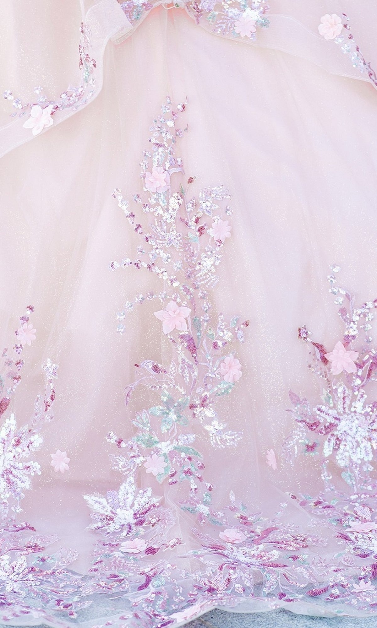 Close-up of Quinceanera Ball Gown 8125J featuring light pink fabric with intricate floral embroidery and sequin accents in pink, purple, and white—ideal for an off-the-shoulder quinceanera look.