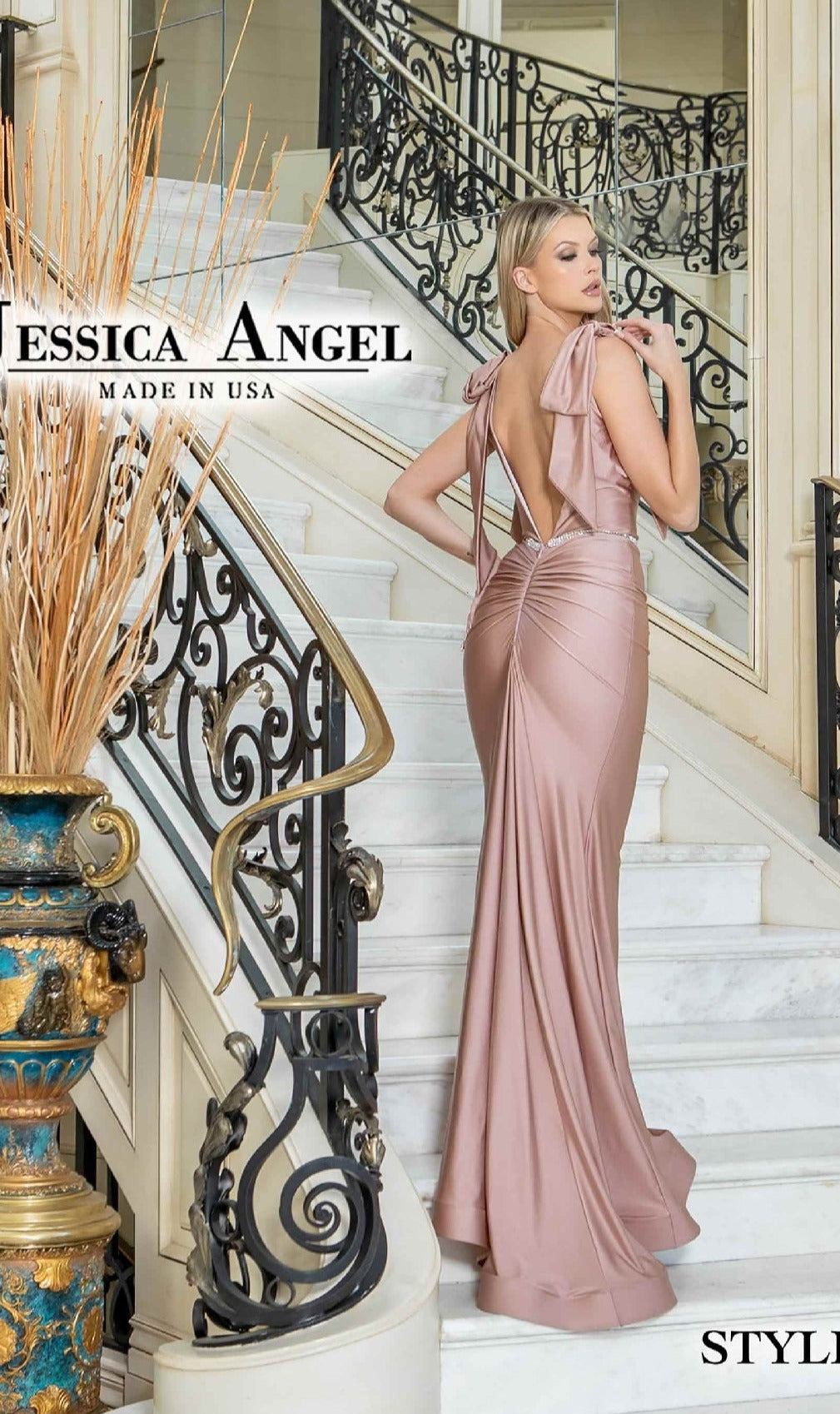 A woman in a pale pink Jessica Angel 819 Shoulder-Bows Long Prom Dress stands on a white marble staircase with ornate black and gold railings.