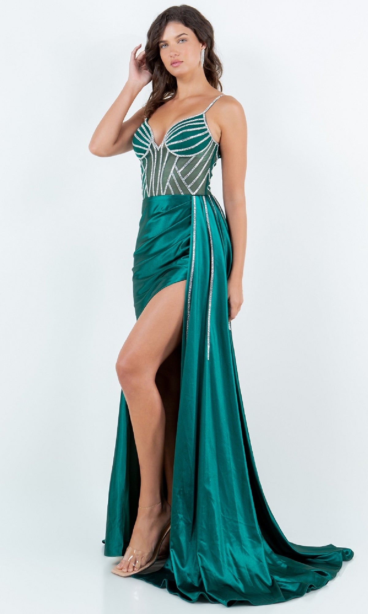 A woman in a sleeveless emerald green Side-Sash Long Prom Gown (Cinderella Couture 8219J) featuring beaded details, a thigh-high slit, and a long train stands against a plain white background.