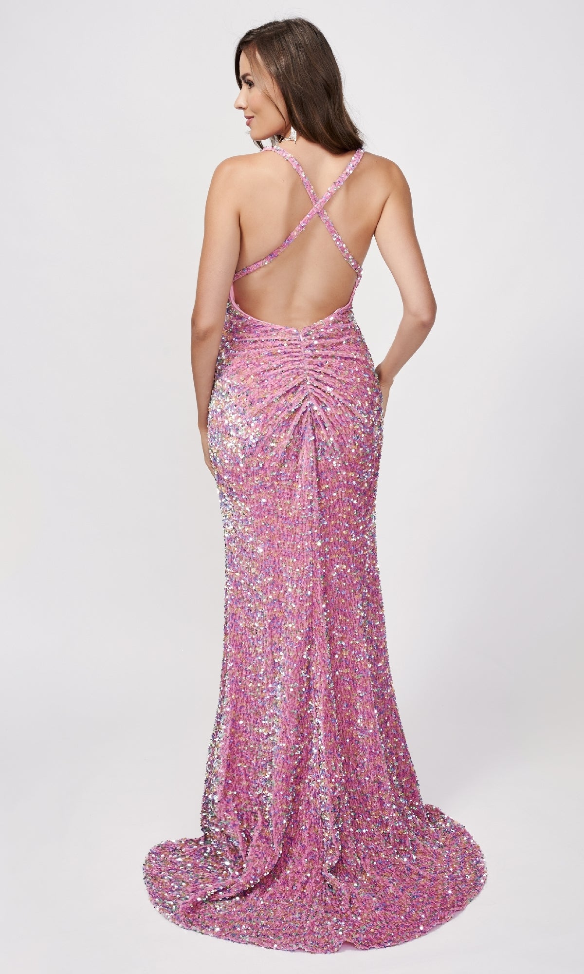Woman in a floor-length Nina Canacci 8233 pink sequin dress with v-neckline, open back, and crisscross straps, standing against a plain white background.