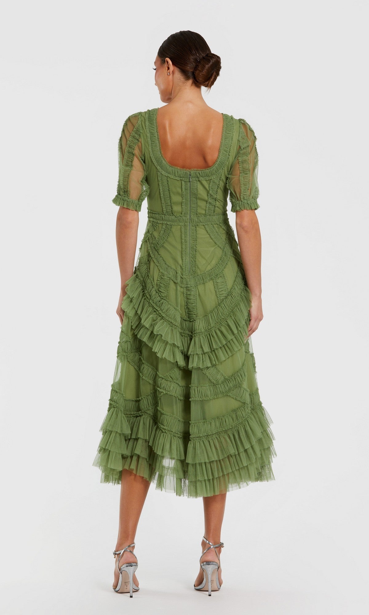 A woman stands on a white background, shown from the back, wearing the Mac Duggal 8248 Ruffled Midi Wedding Guest Dress in green with short sleeves and silver high-heeled sandals—a chic choice for any semi-formal occasion.