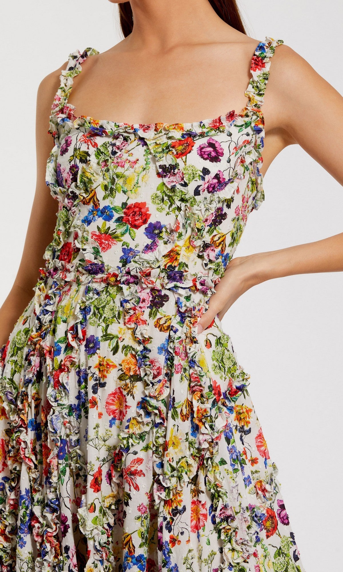 A woman poses with one hand on her hip, wearing the Mac Duggal 8256 Floral Wedding Guest Dress, a sleeveless ruffled scoop-neck dress with a colorful floral pattern.