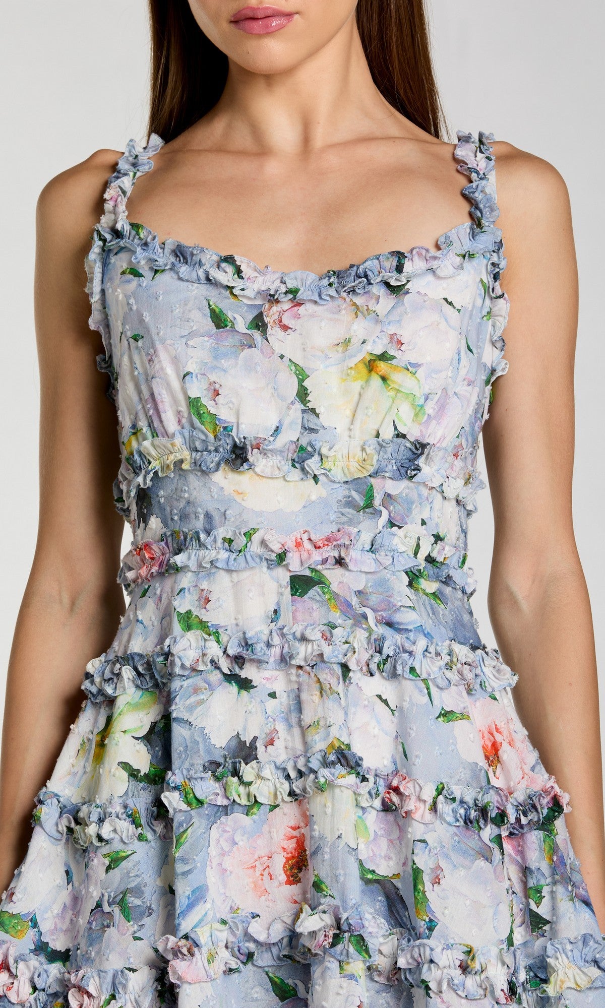 Woman wearing the Mac Duggal 8257 short party dress, featuring sleeveless design, floral print, ruffled trim, and tiered layers. Shown from shoulders to above the knees.