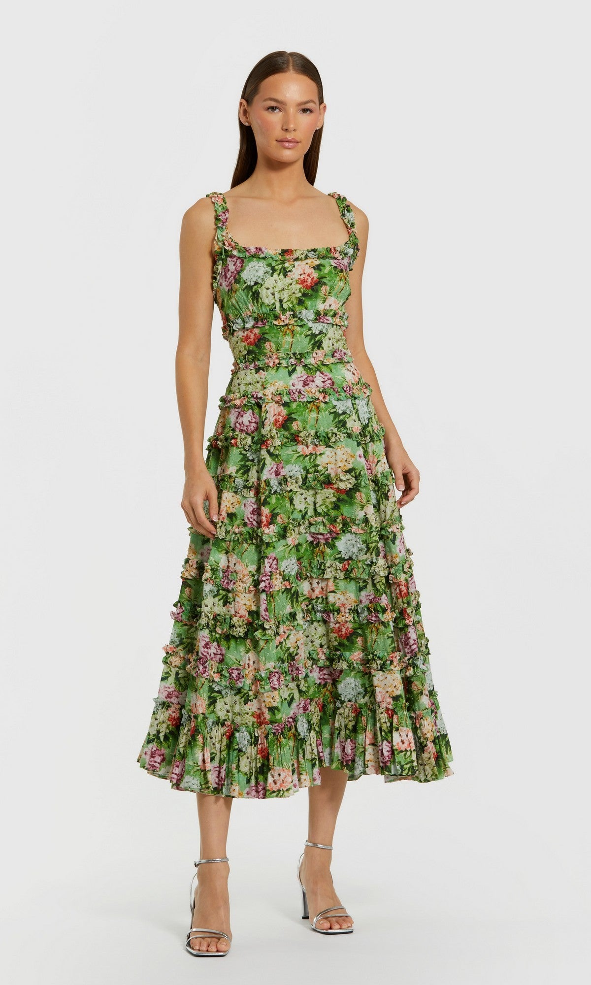 Woman in the Mac Duggal 8263 Midi Wedding Guest Dress in Green Multi with a fitted bodice and ruffled skirt, paired with silver strappy heels, standing against a plain background.