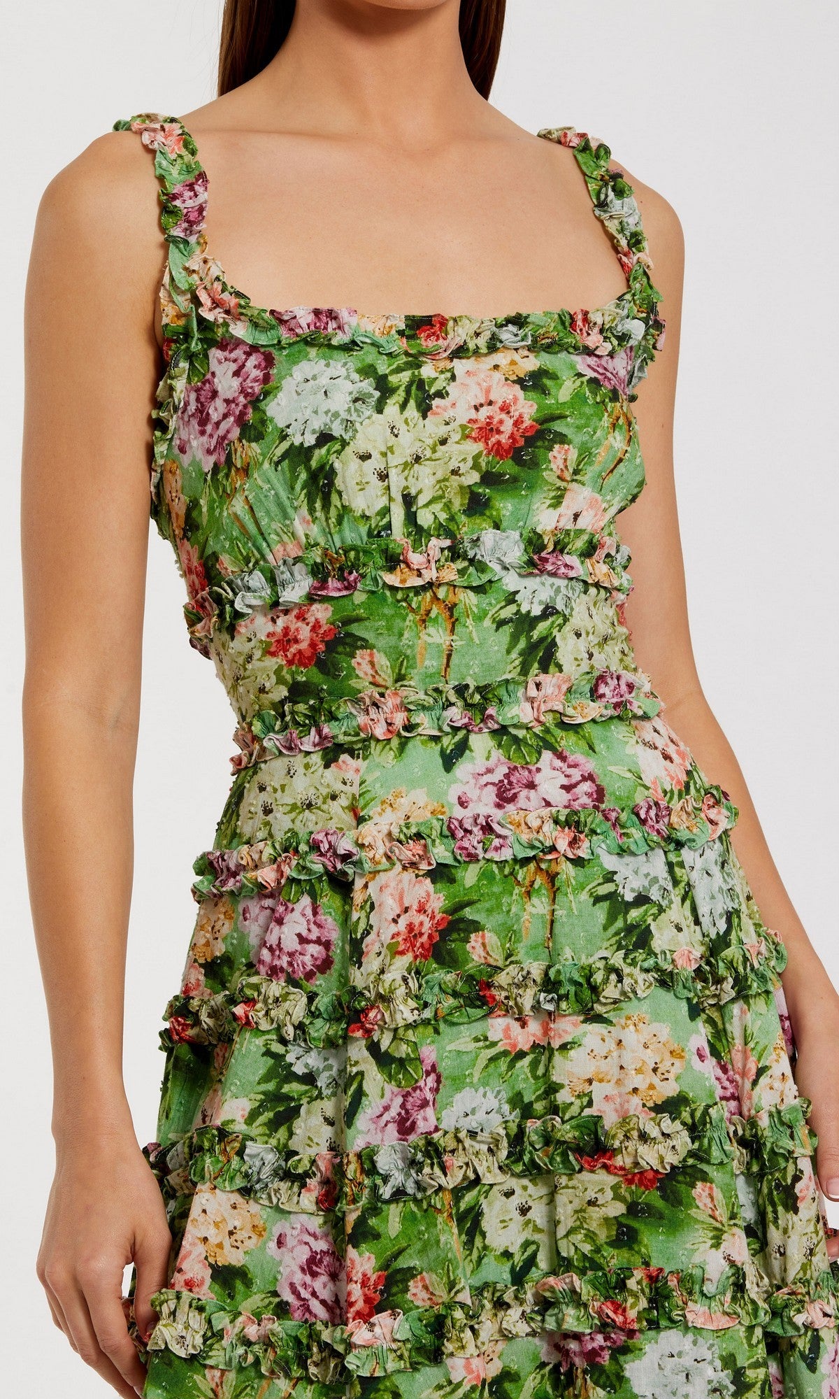 A woman wears the Midi Wedding Guest Dress: Mac Duggal 8263, a sleeveless cotton midi dress with a square neckline, tiered detailing, and a colorful floral print on a green background.