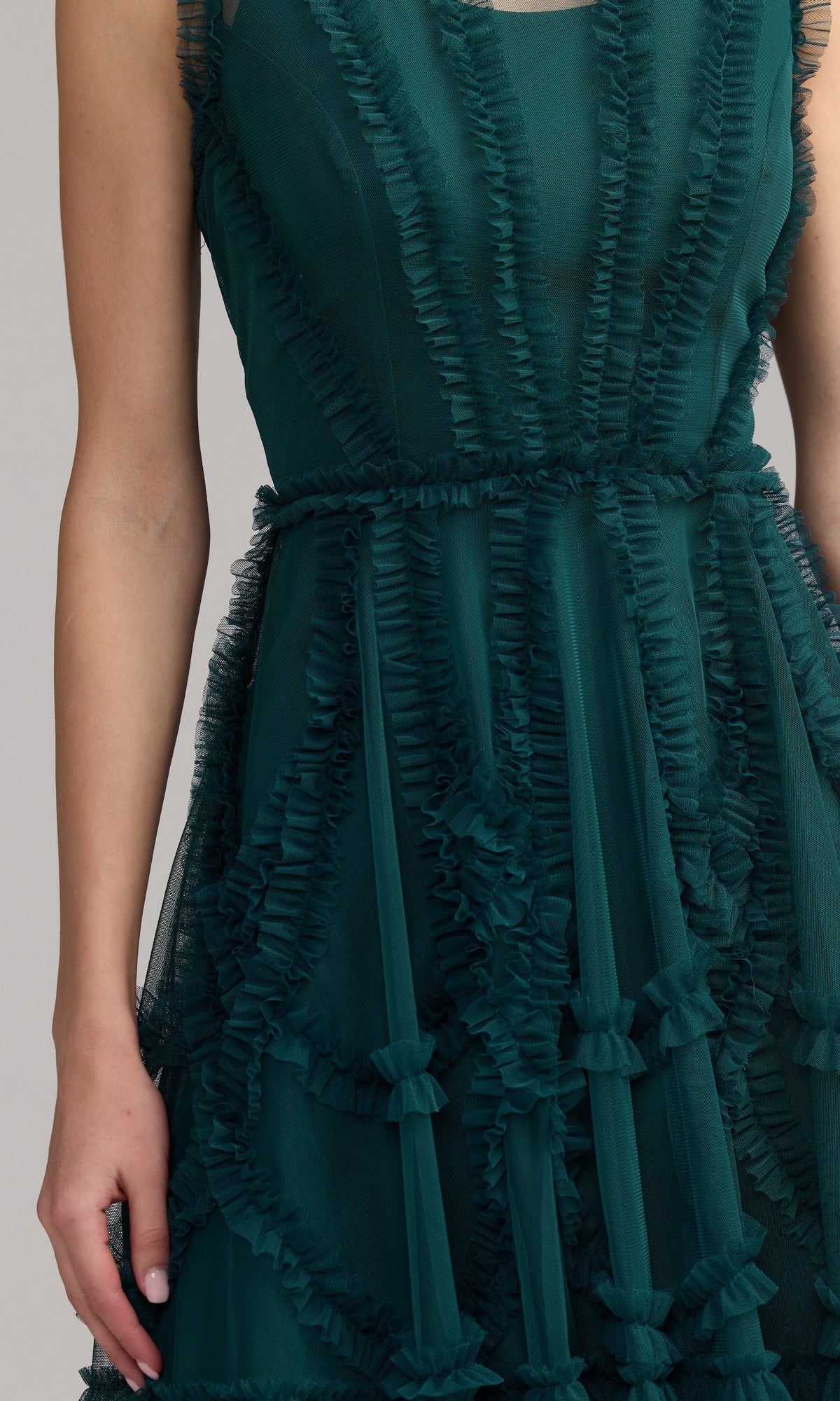 A person wearing the Mac Duggal 8289 Short Ruffled Wedding Guest Dress, a sleeveless dark green semi-formal dress with layered ruffle detailing, shown from shoulders to knees.