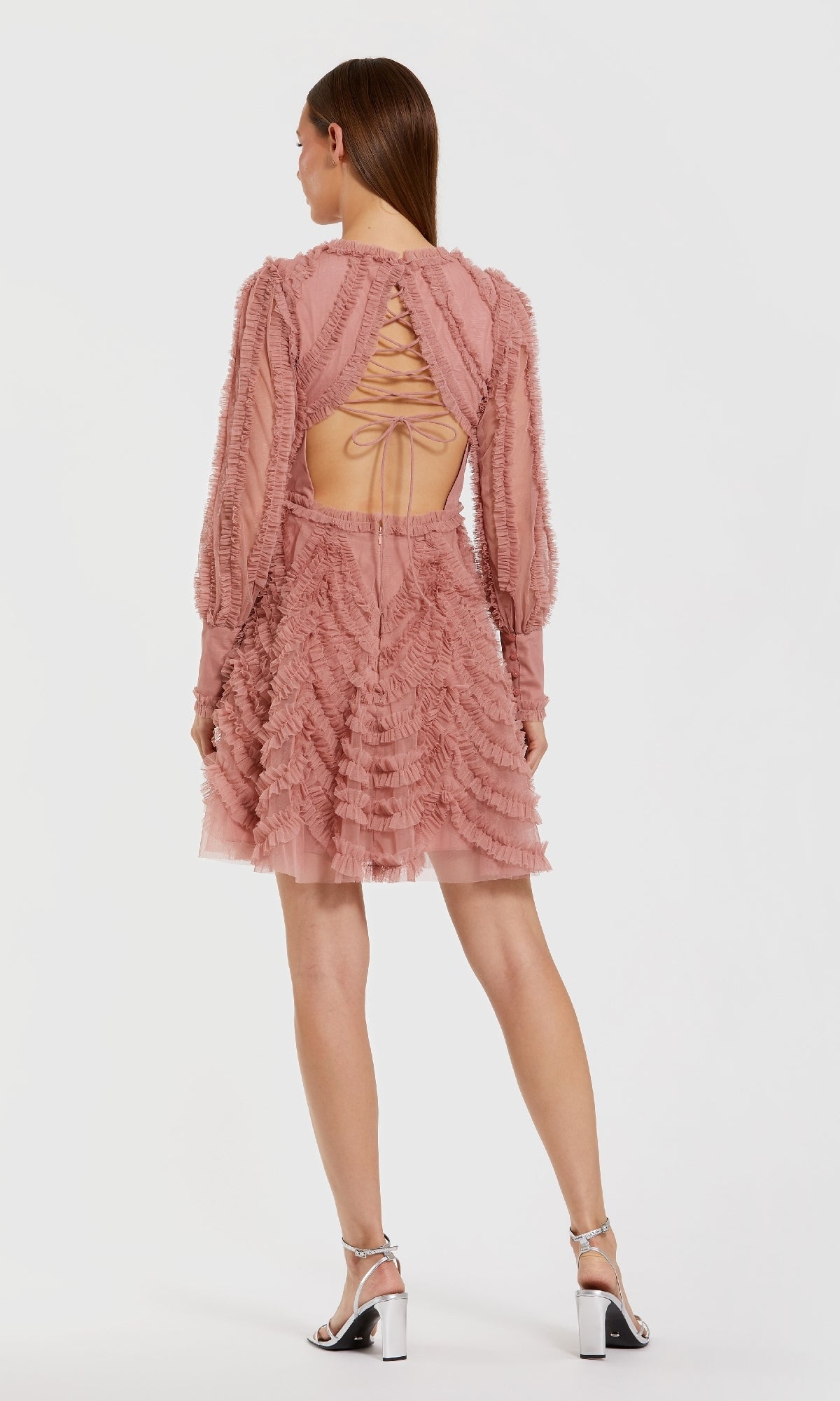 The back of a pink short dress worn by a model on a white background