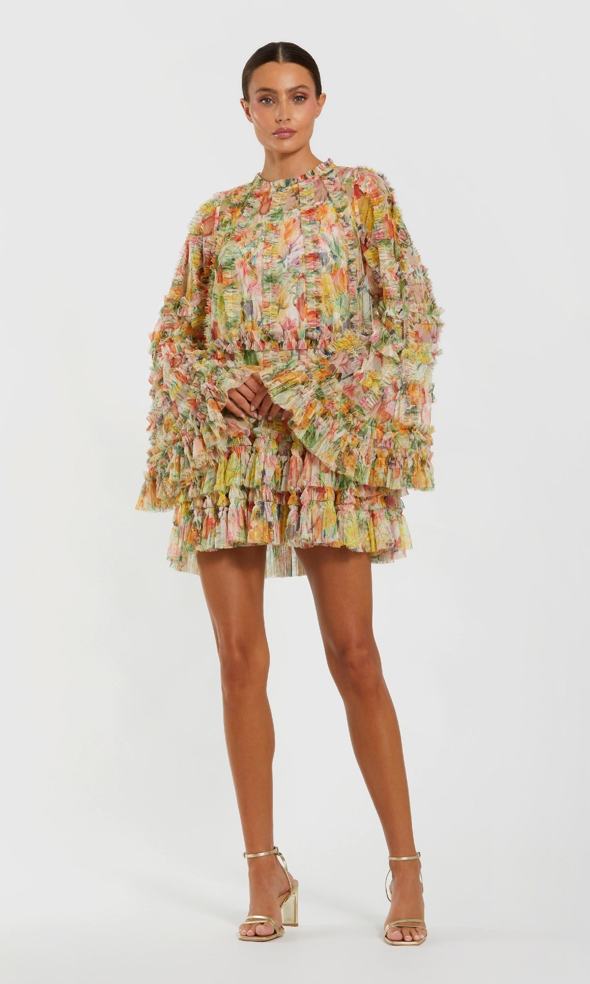 A woman poses against a white background, wearing the Mac Duggal 8300 Bell-Sleeve Floral Wedding Guest Dress, paired with gold high-heeled sandals.