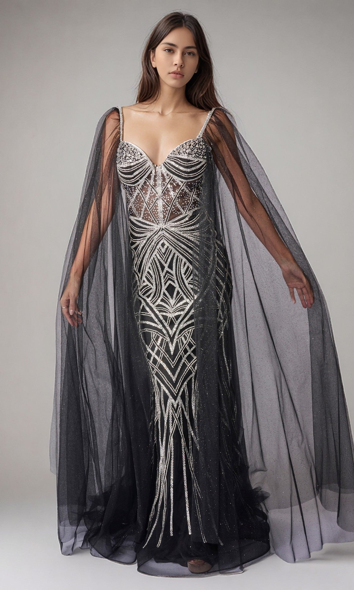 A woman wears the Nina Canacci 8305 long formal dress in black/silver, featuring intricate silver geometric beadwork, a fitted floor-length silhouette, and sheer flowing cape sleeves.