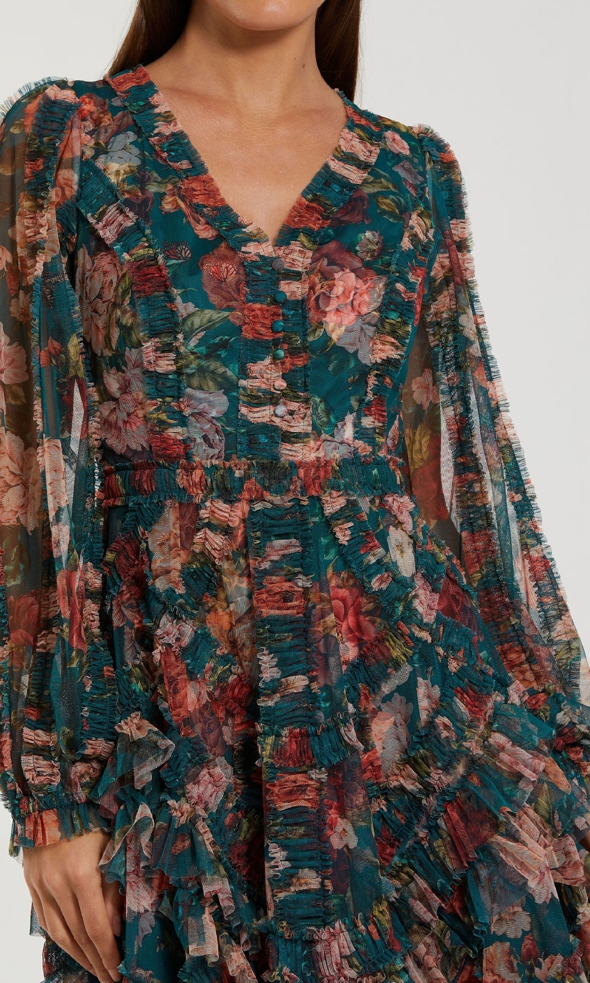 A person wears the Mac Duggal 8348 Floral Wedding Guest Dress, featuring long sleeves, a v-neck, ruffles, and an a-line skirt in green, pink, and red floral print. Their face is not visible.