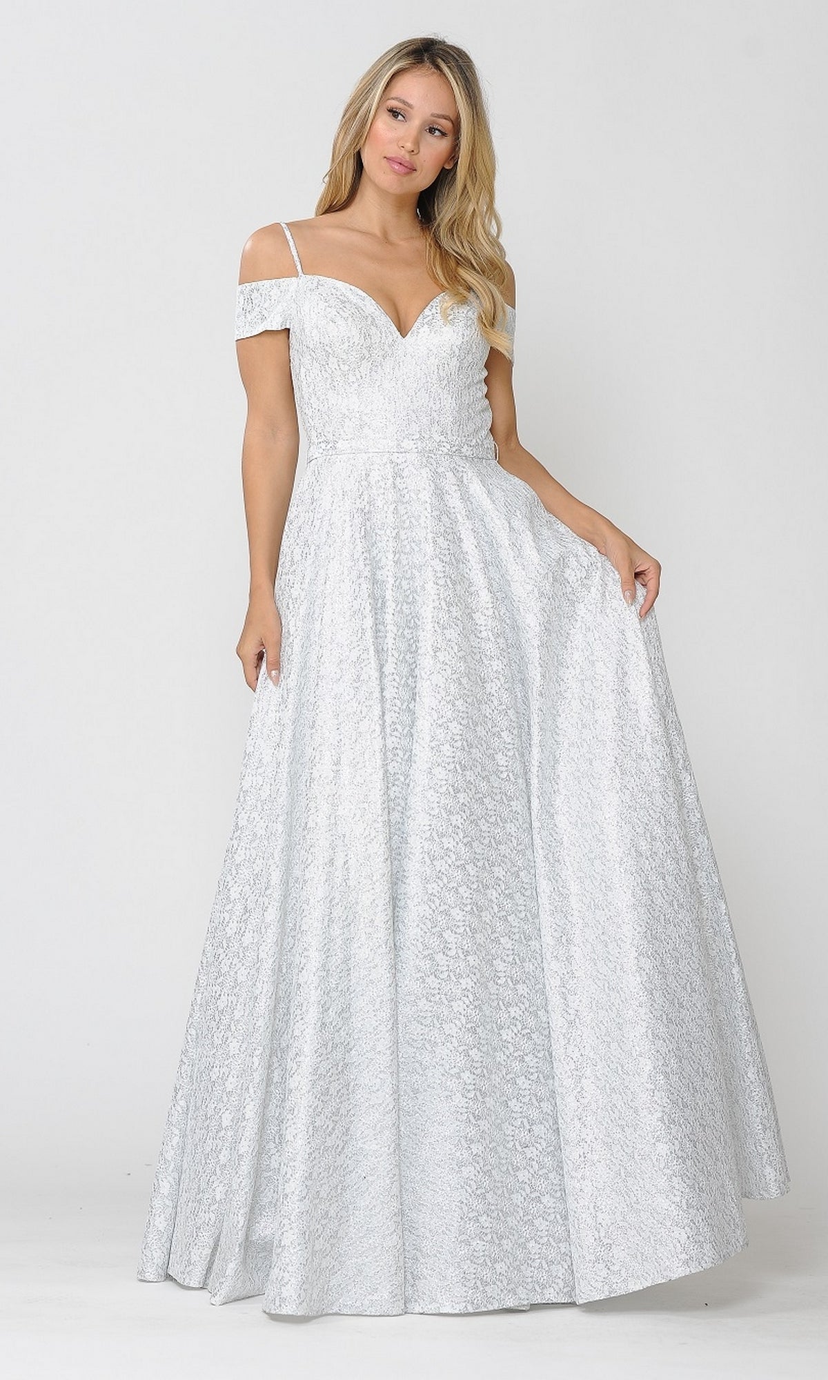 A woman in the Cold-Shoulder Silver and White Long Prom Gown 8380, an off-the-shoulder, floor-length dress with lace texture, stands against a plain white background.