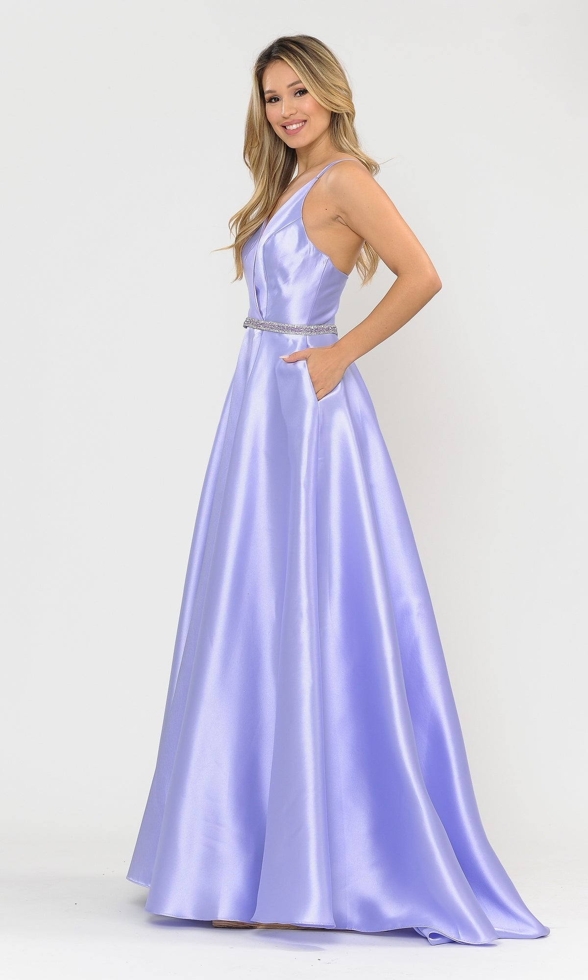 A woman wears the Long A-Line Mikado Prom Gown 8690, a sleeveless, floor-length light purple dress with pockets and a beaded waist, standing against a plain white background.