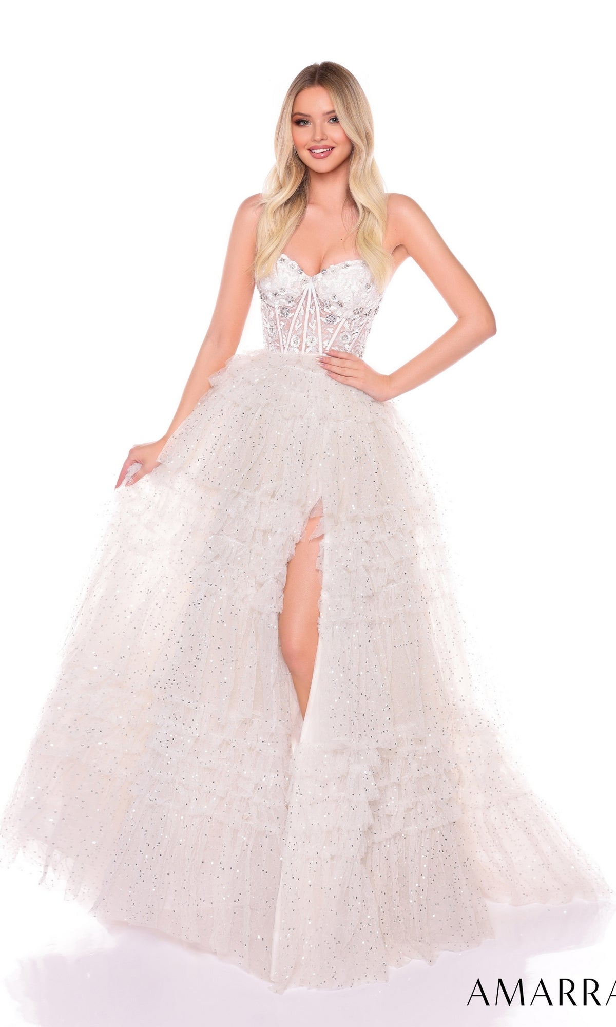 A woman wears the Long Formal Dress 88099 by Amarra, a strapless ball gown with a fitted sheer corset bodice, ruffle layered tulle skirt with high slit, and sparkling accents for an elegant, glamorous look.