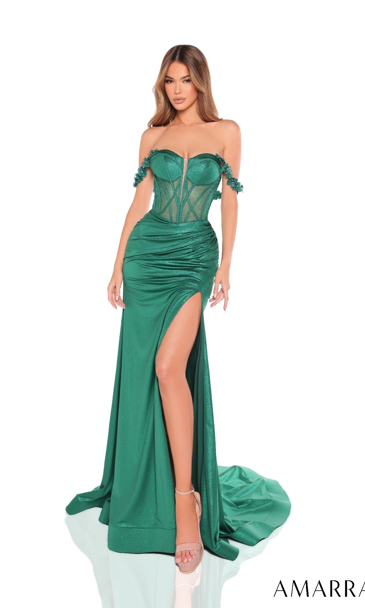 A woman models the Amarra 88243, a long prom dress featuring a strapless fitted emerald green design with a sheer corset bodice, high-leg slit, and floor-length skirt.