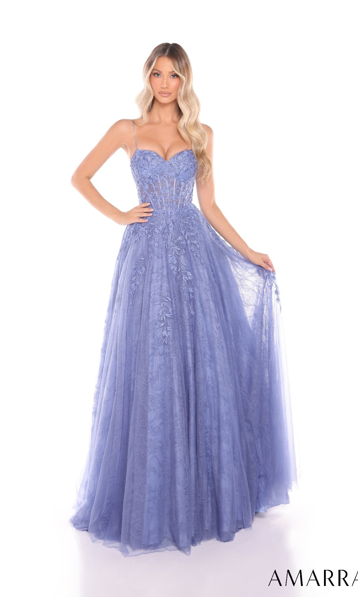 A woman poses against a white background wearing the Amarra 88413 Lace Prom Ball Gown, a floor-length lavender dress with spaghetti straps and delicate floral lace appliques.