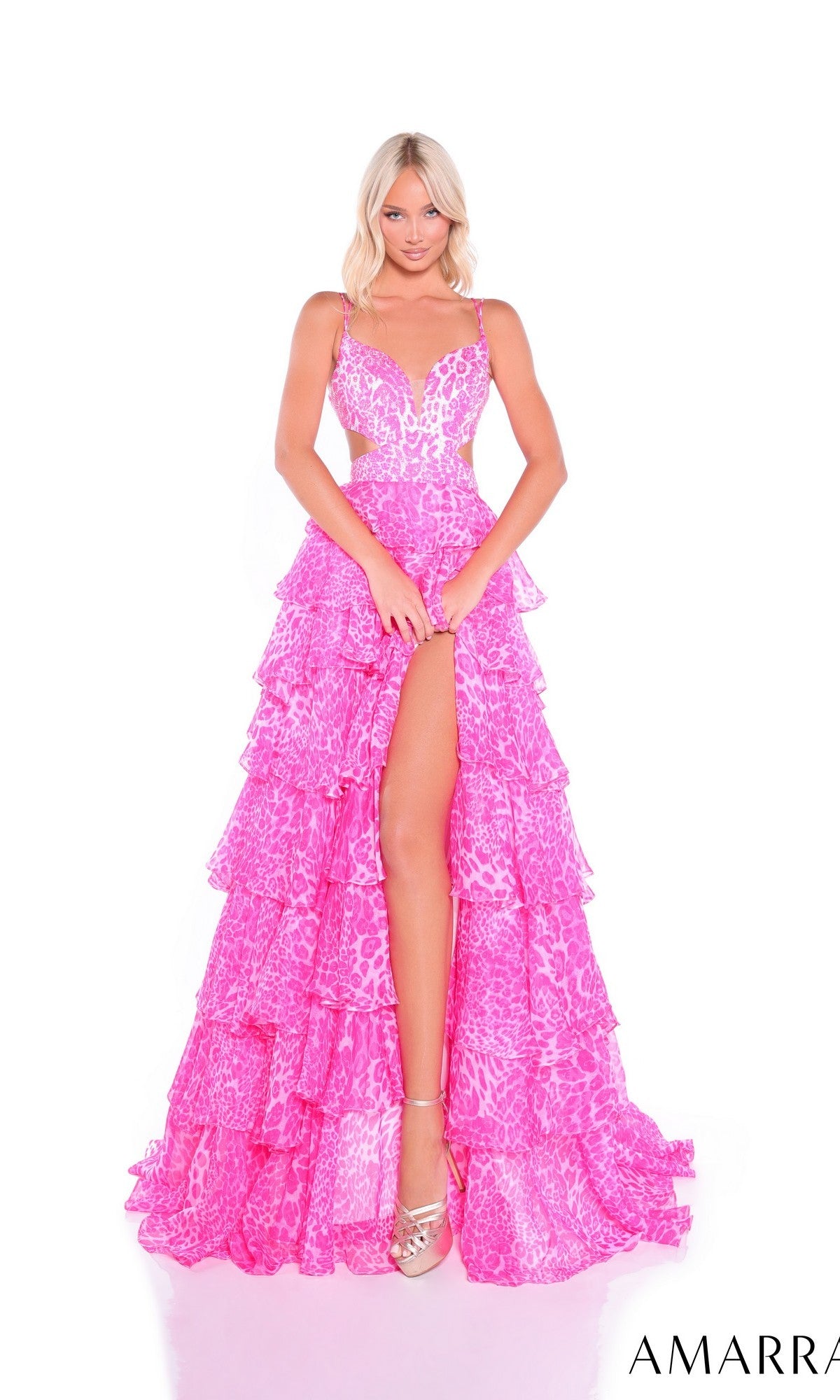 A woman stands facing forward against a white background, wearing the Amarra 89407 long prom dress—a striking, bright pink tiger print ball gown with tiered ruffles and a high slit.