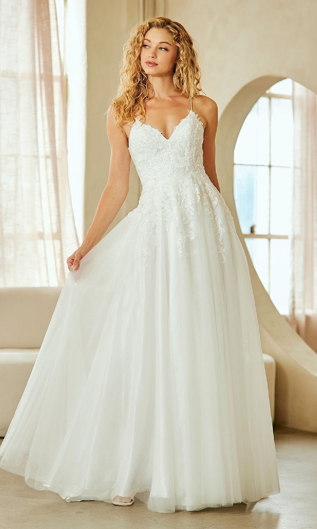 Woman wearing a long white tulle ball gown with a monotone beige background.