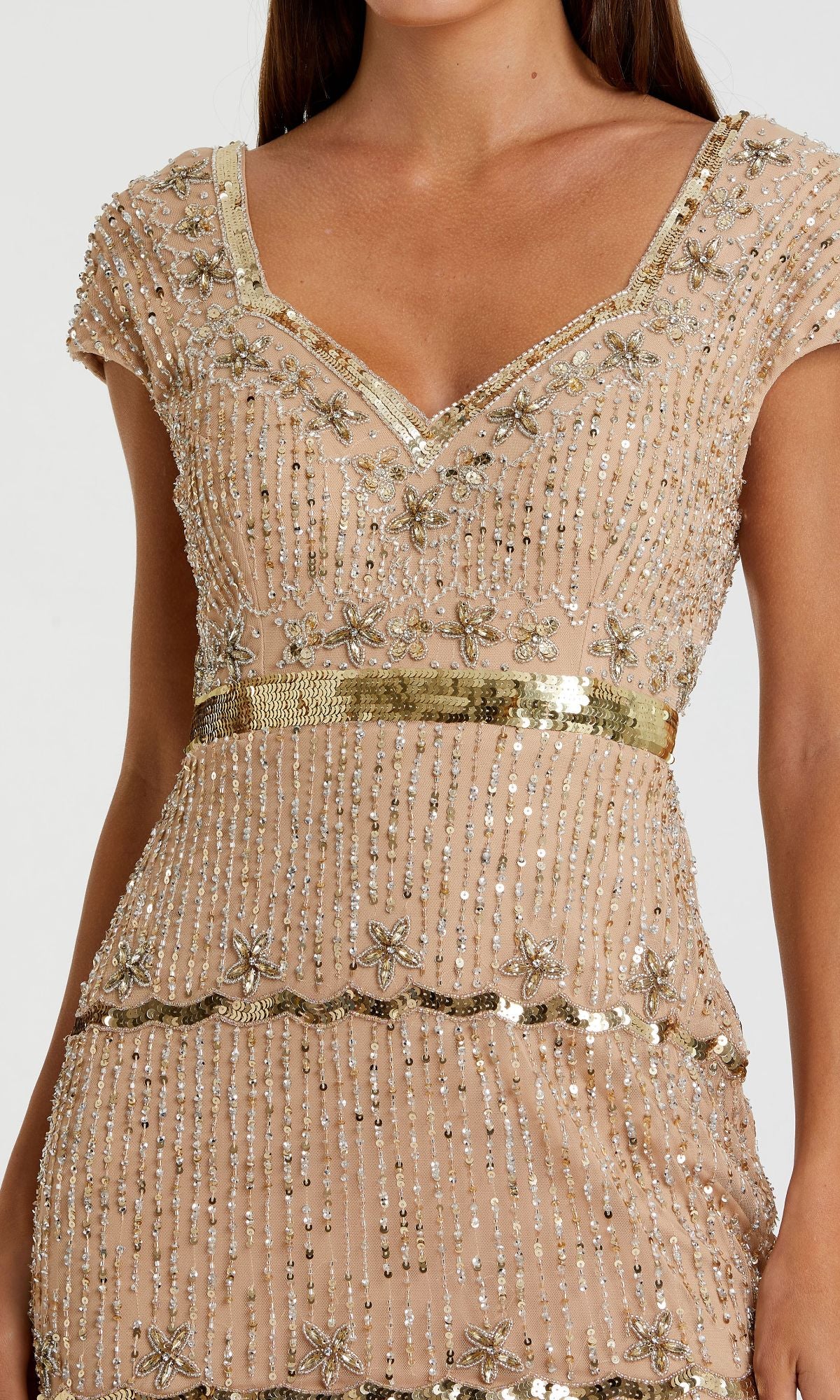 A woman in the Mac Duggal 9089 cap-sleeve beaded formal dress, light beige with gold trim and intricate bead and sequin floral embellishments.