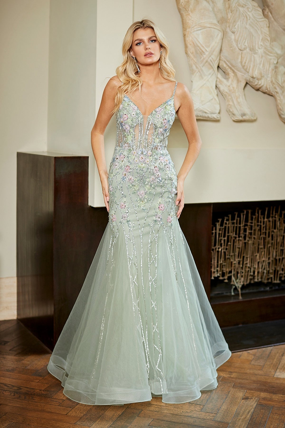 Amelia Couture 9104 is a pale green floral mermaid prom dress with a plunging neckline, intricate embroidery, and silver beaded accents.