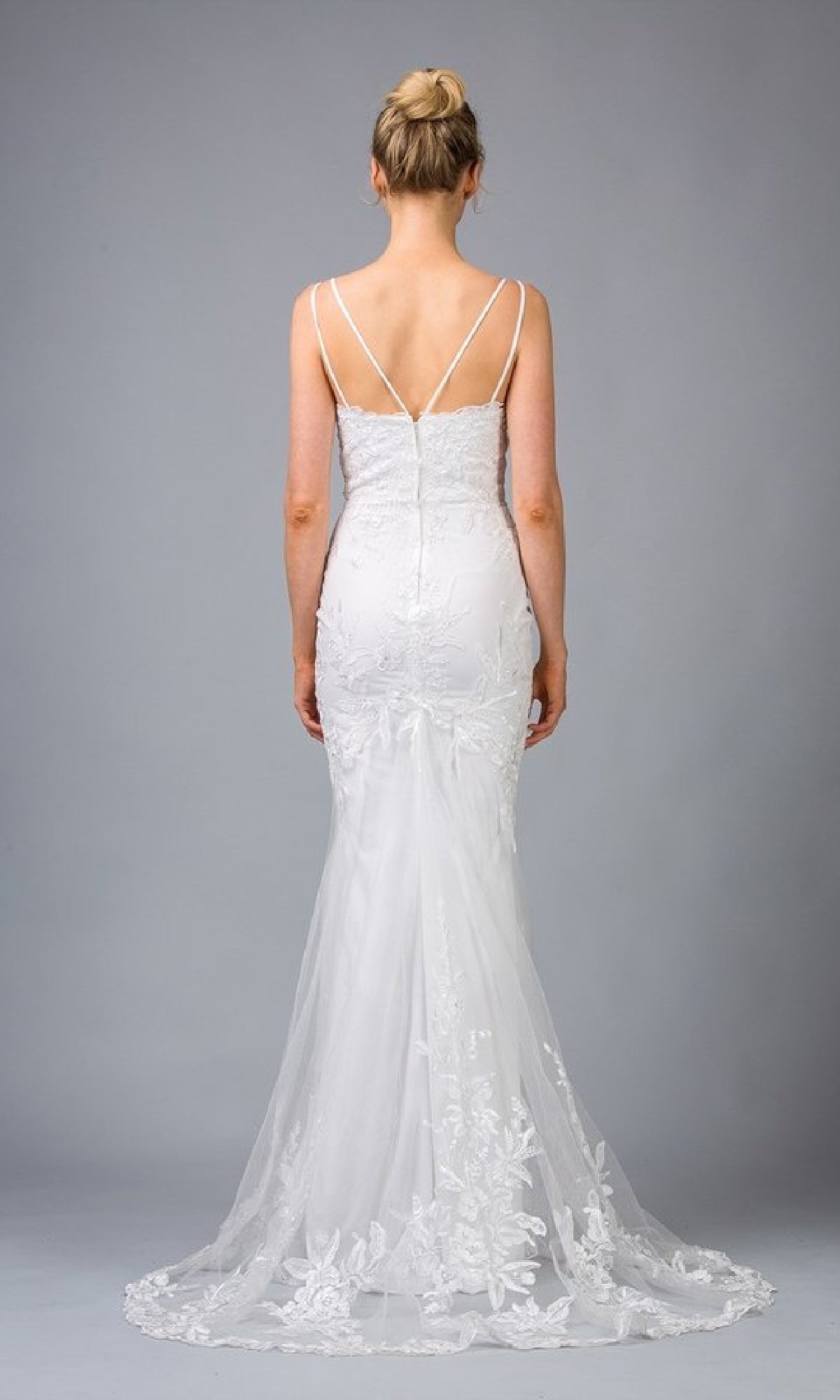 A woman stands facing away, wearing the Eureka 9130 Long Embroidered-Lace Prom Dress with thin straps and a long train, set against a plain gray background.