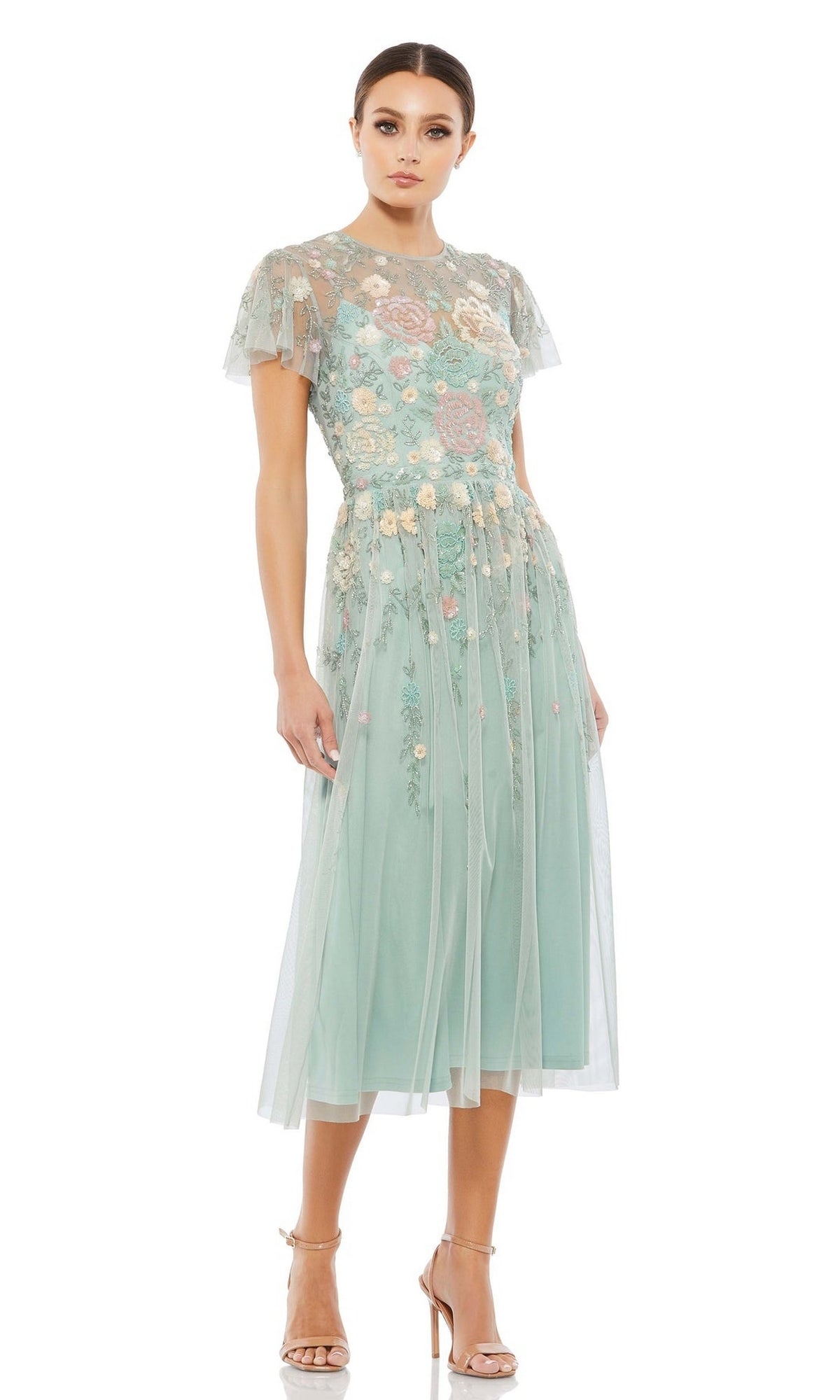 A woman wears the Knee Length Wedding Guest Dress 9134 by Mac Duggal in mint green with floral embroidery, sheer short sleeves, and nude high heels—ideal for wedding guests—standing against a white background.