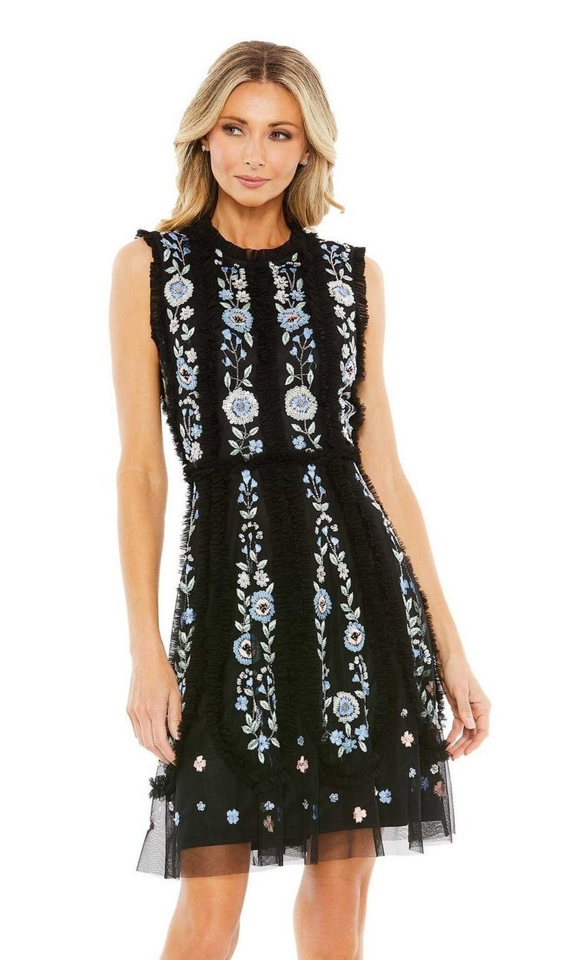 A woman stands against a white background wearing the Mac Duggal 9135 Embroidered Short Party Dress—a sleeveless black cocktail dress with intricate blue and white floral embroidery.