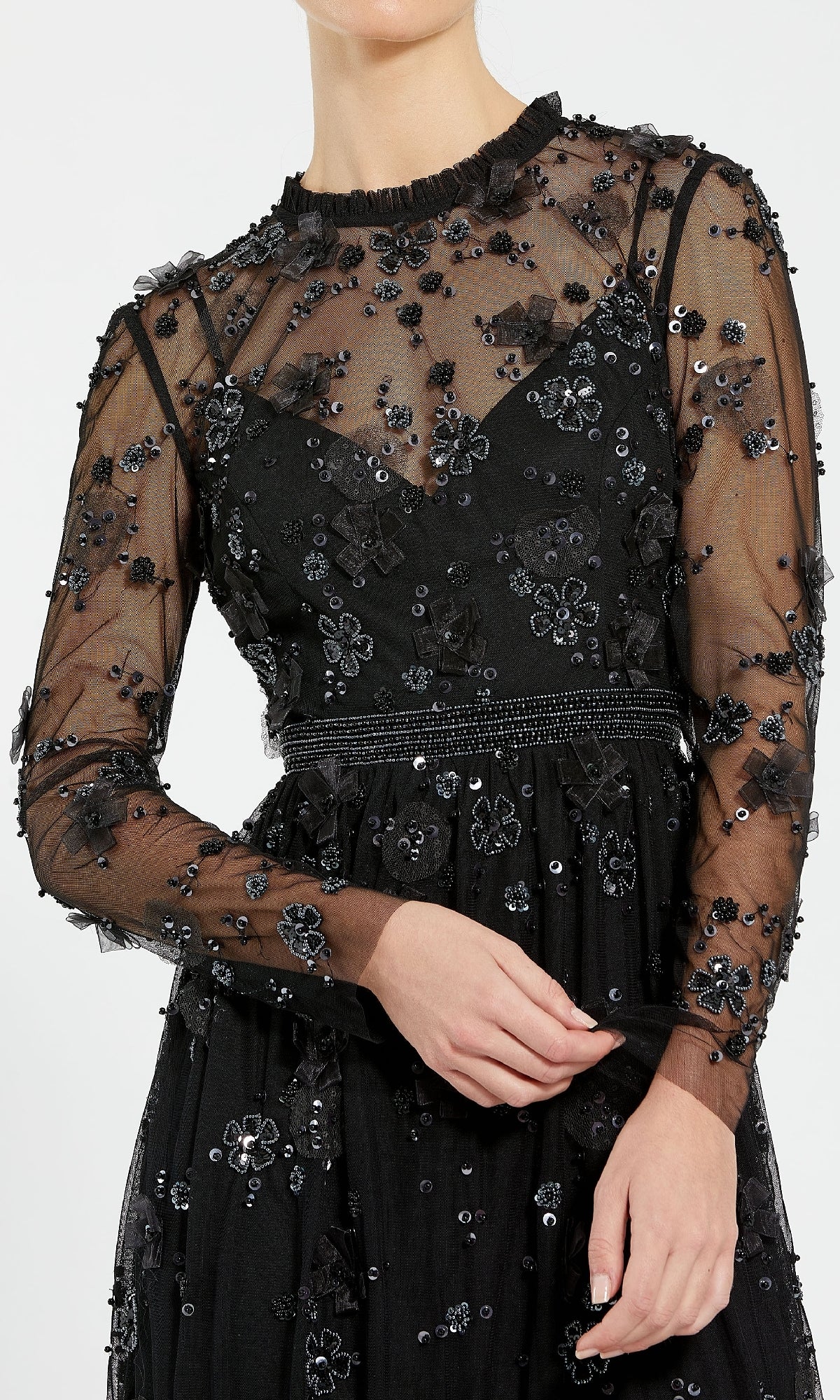Someone wearing the Mac Duggal 9140 Short Black Wedding Guest Dress, featuring long sheer sleeves, floral embroidery, sequins, a fitted waistband, layered fabric, and a high neckline—an elegant choice for wedding guests.