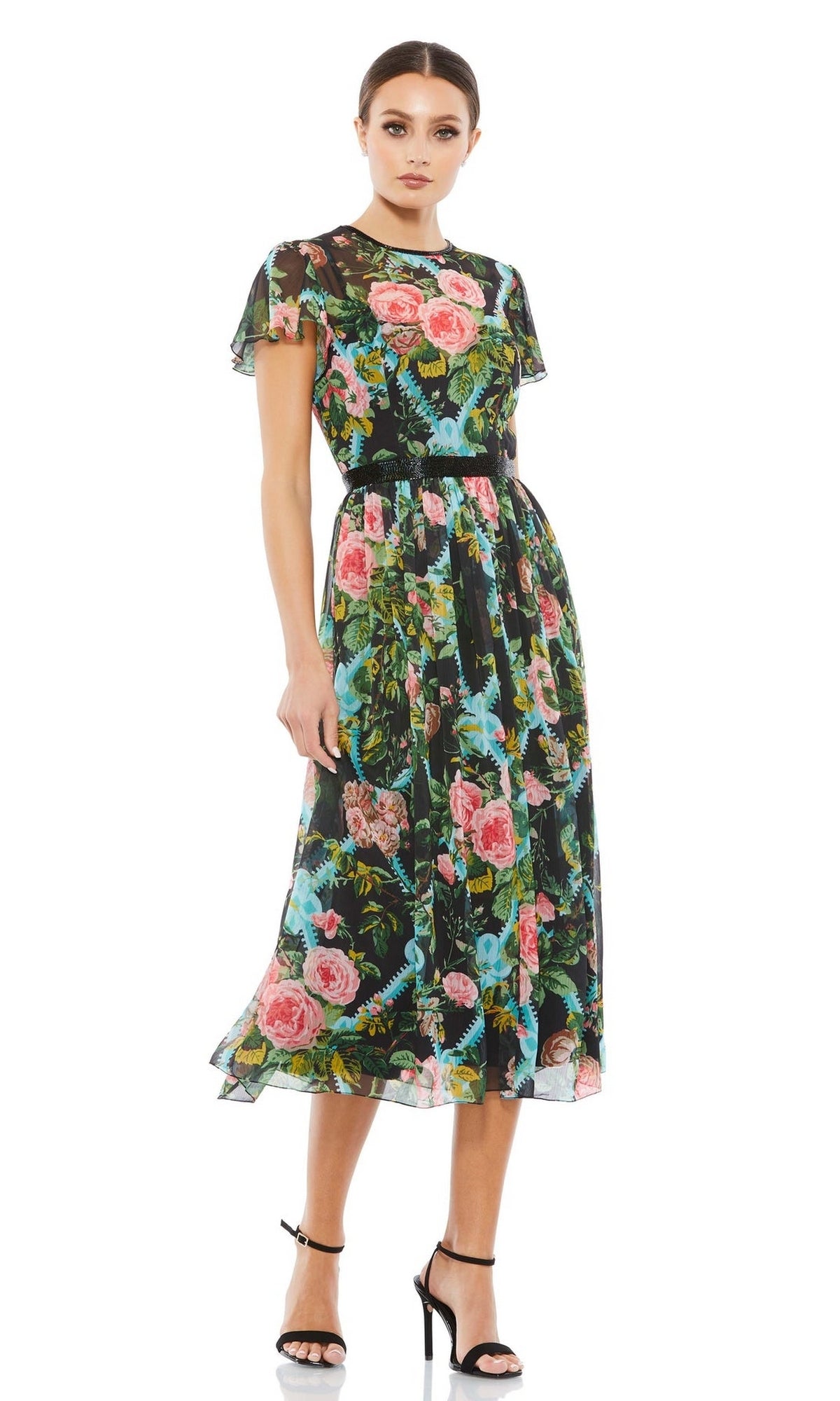 A woman in the Mac Duggal 9149 Print Midi Wedding-Guest Dress with short sleeves and black high-heeled sandals stands against a white background.