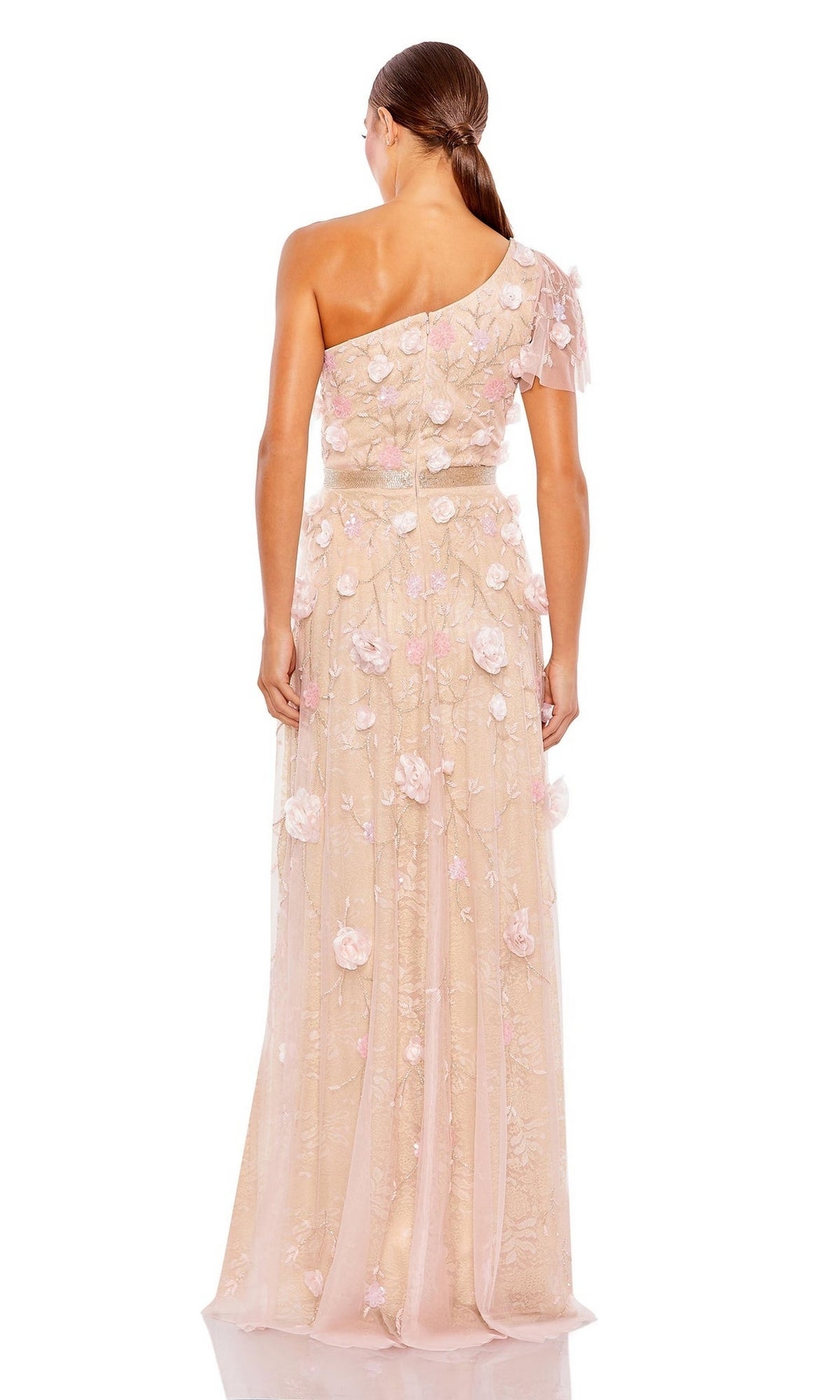 A woman with her hair in a low ponytail stands with her back to the camera, wearing the Long Formal Dress 9165 by Mac Duggal—a light pink, one-shoulder gown adorned with floral appliqués.