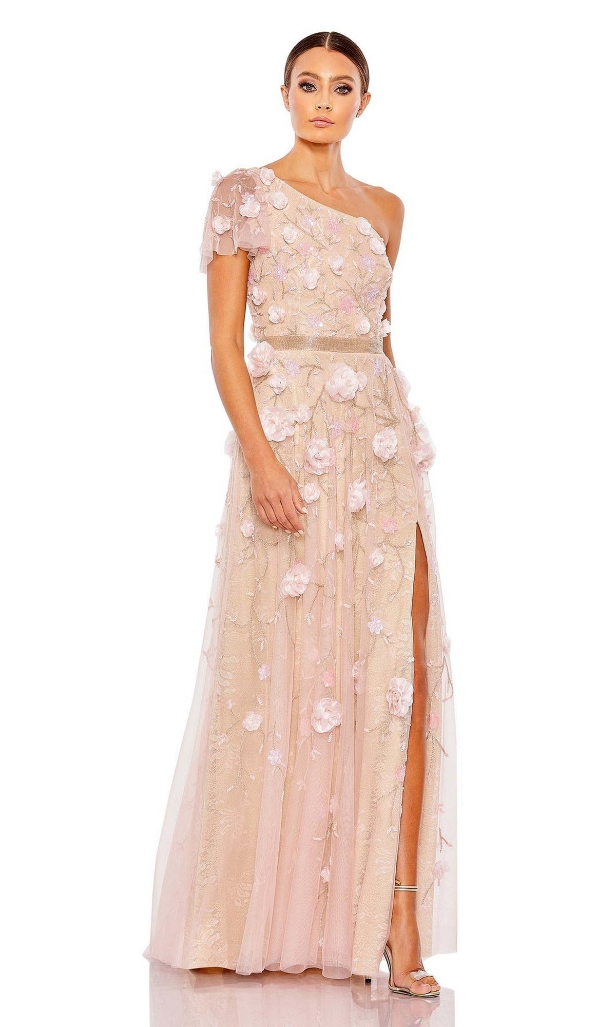 A woman models the Long Formal Dress 9165 by Mac Duggal, featuring blush pink fabric, a one-shoulder design, floral appliqués, sheer overlay, and a thigh-high slit against a white background.