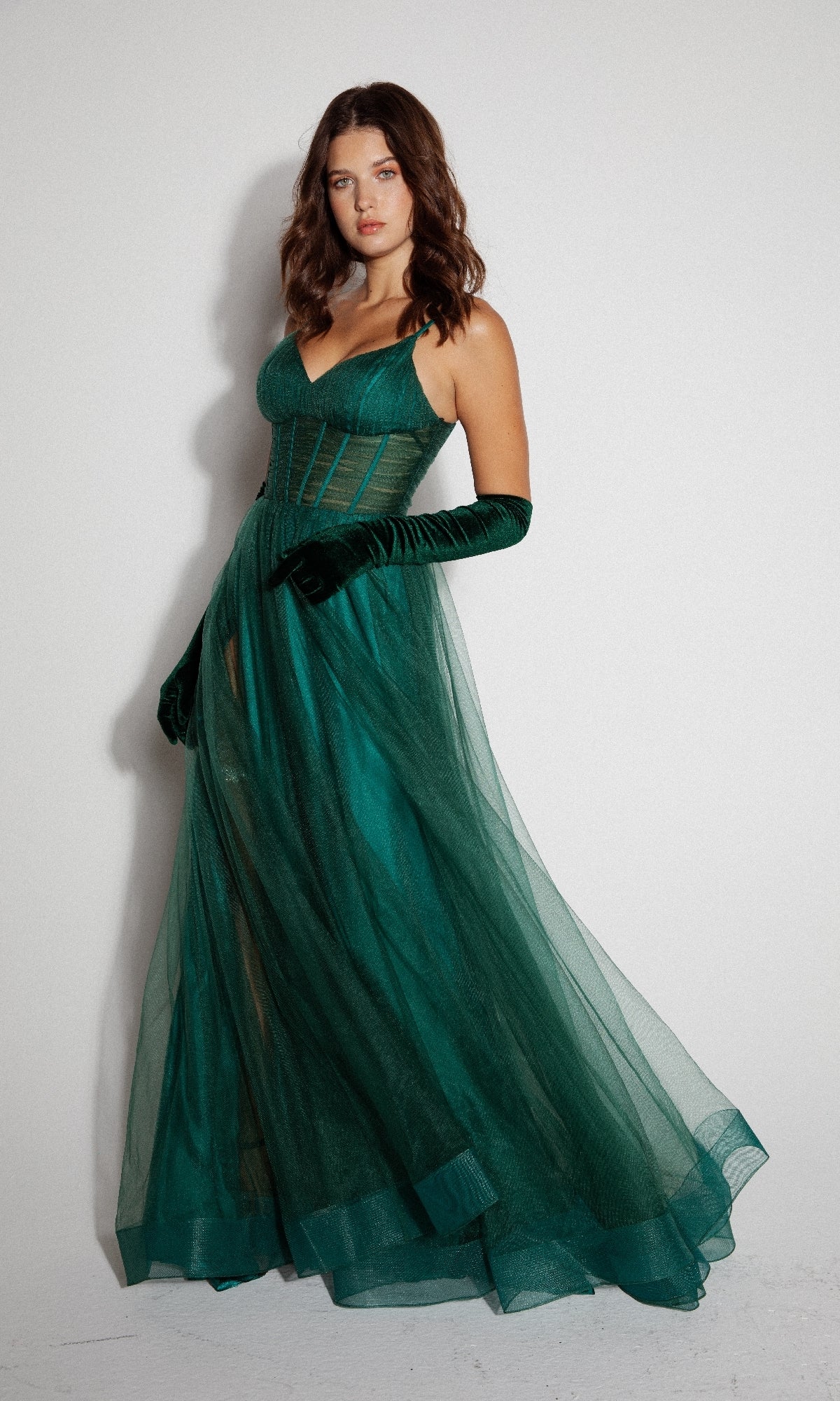 A woman wears the Eureka 9177 Corset Long Tulle Prom Ball Gown in green with matching velvet gloves, standing against a plain white background.