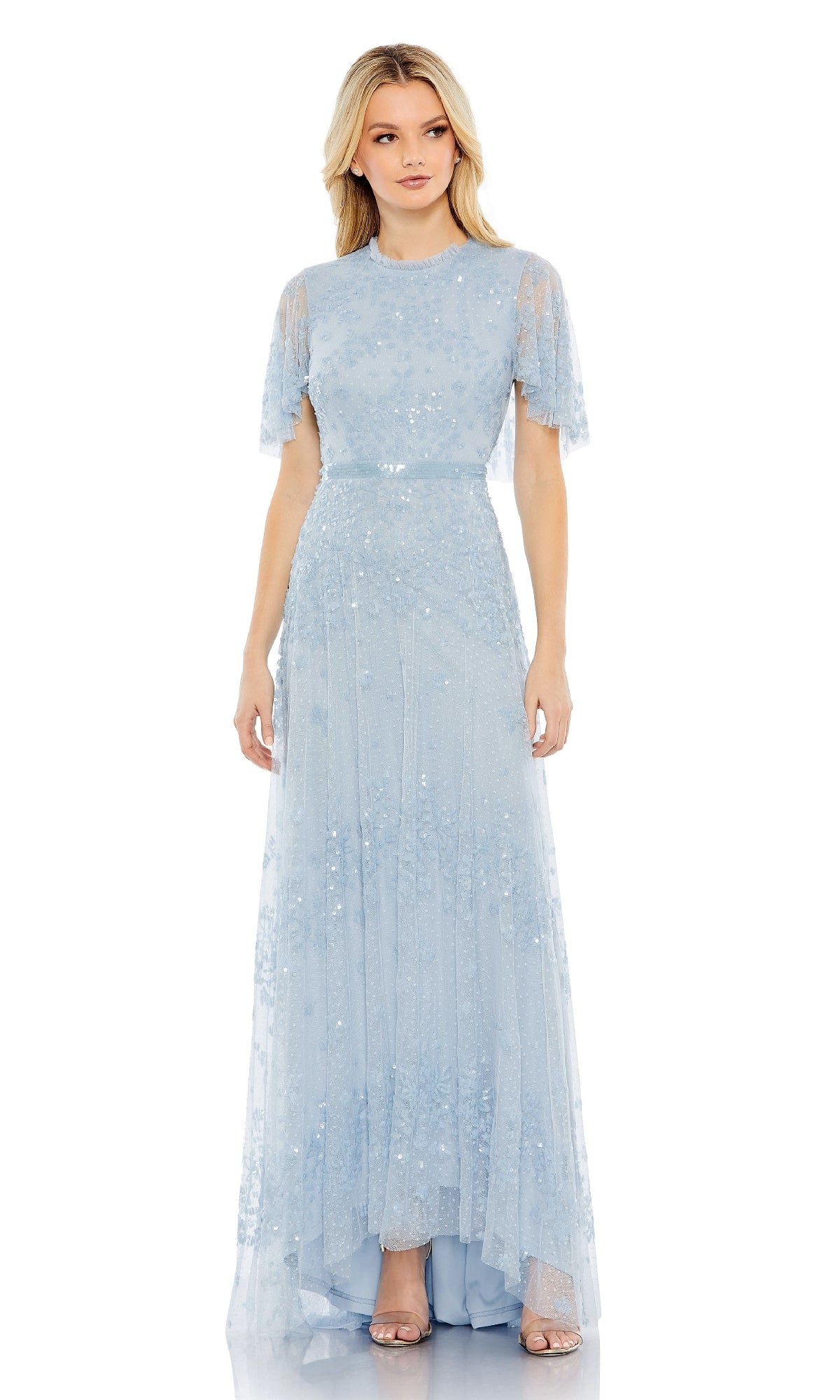 A woman stands against a white background wearing the Mac Duggal 9192: a floor-length, short-sleeve blue formal dress with sequin embellishments.