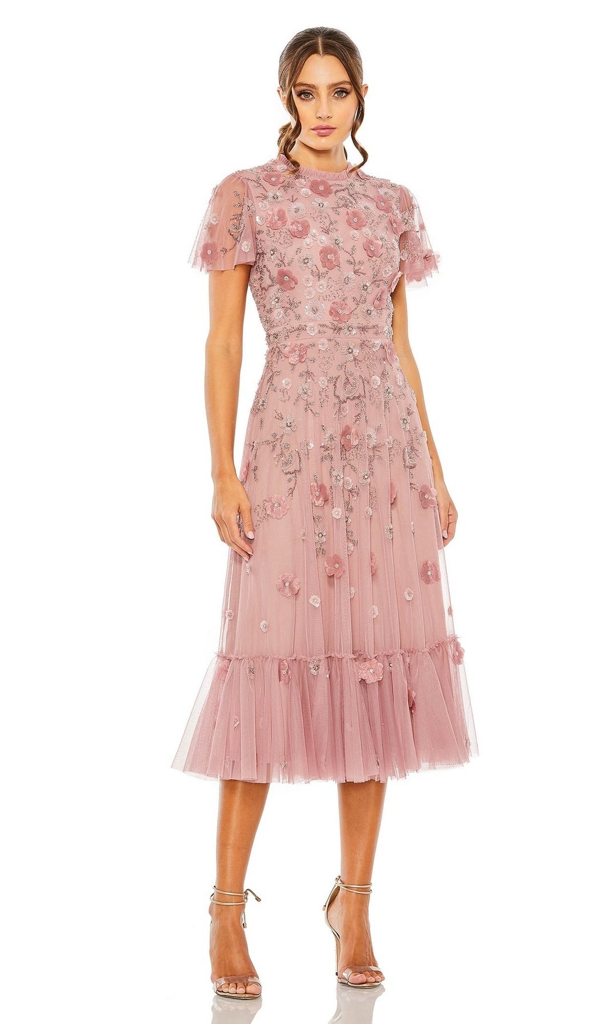 A woman wears the Mac Duggal 9212 Floral Midi Wedding-Guest Dress—pink, knee-length, with short sleeves, embroidery, airy tulle layers—and strappy high-heeled sandals.