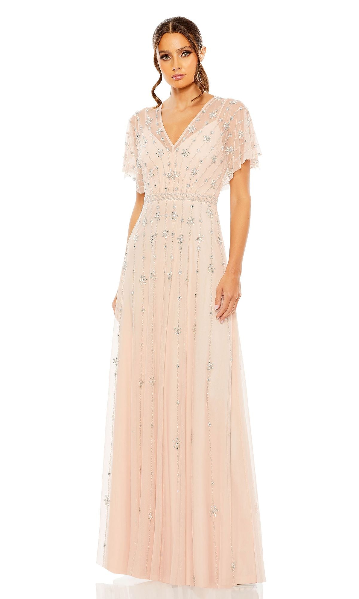 A woman in the Mac Duggal 9223 Short Sleeve Long Formal Dress—light pink, floor-length, with silver floral embellishments—poses against a white background.