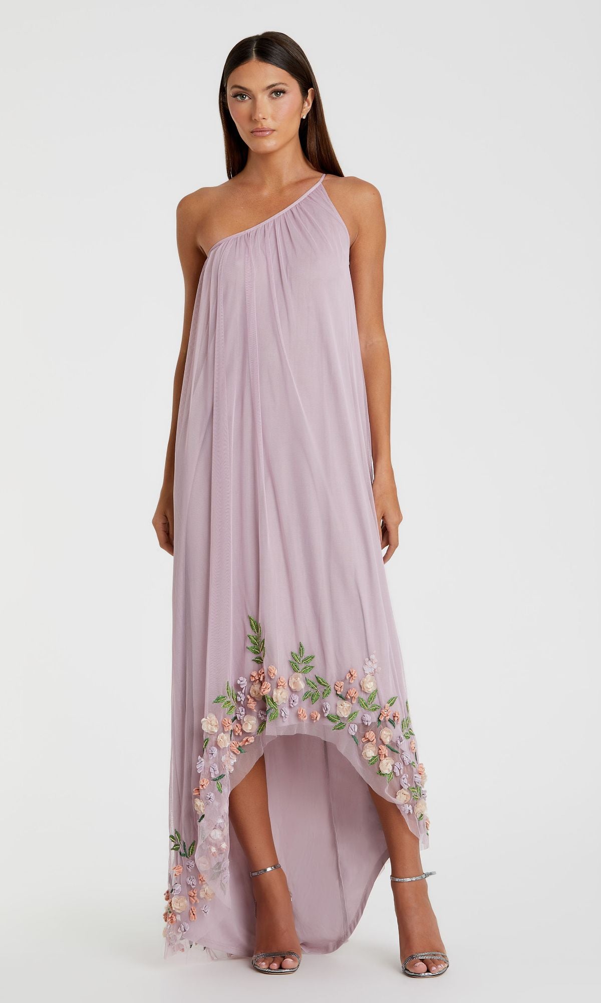 Woman in the Mac Duggal 9236 Beaded Long Shift Formal Dress, featuring a lavender one-shoulder design and floral embroidery along the hem, standing against a plain white background.