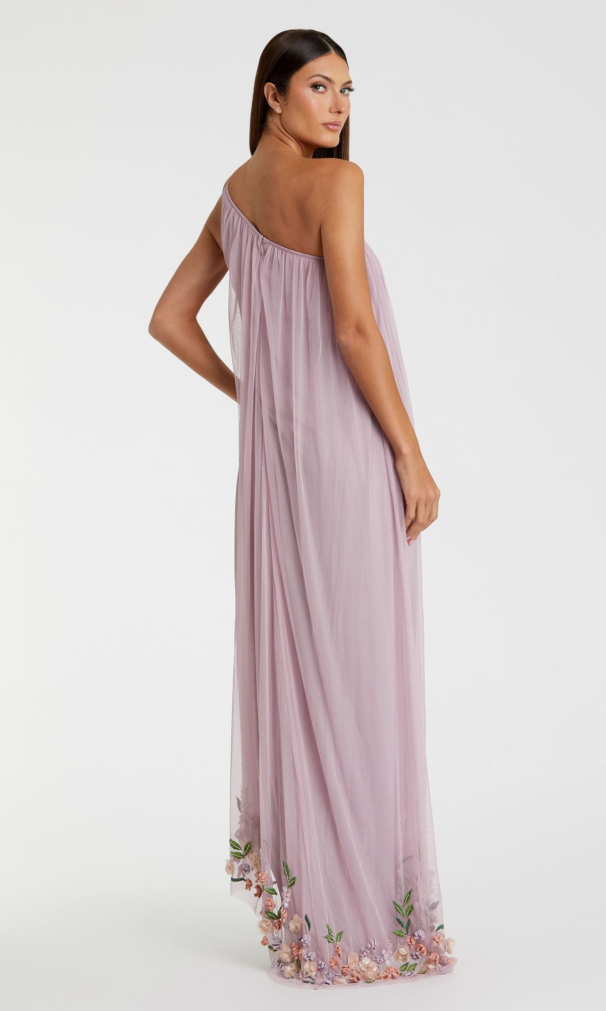 A woman poses against a white background wearing the Mac Duggal 9236 Beaded Long Shift Formal Dress—a stylish, one-shoulder lilac gown with floral embroidery along the hem.