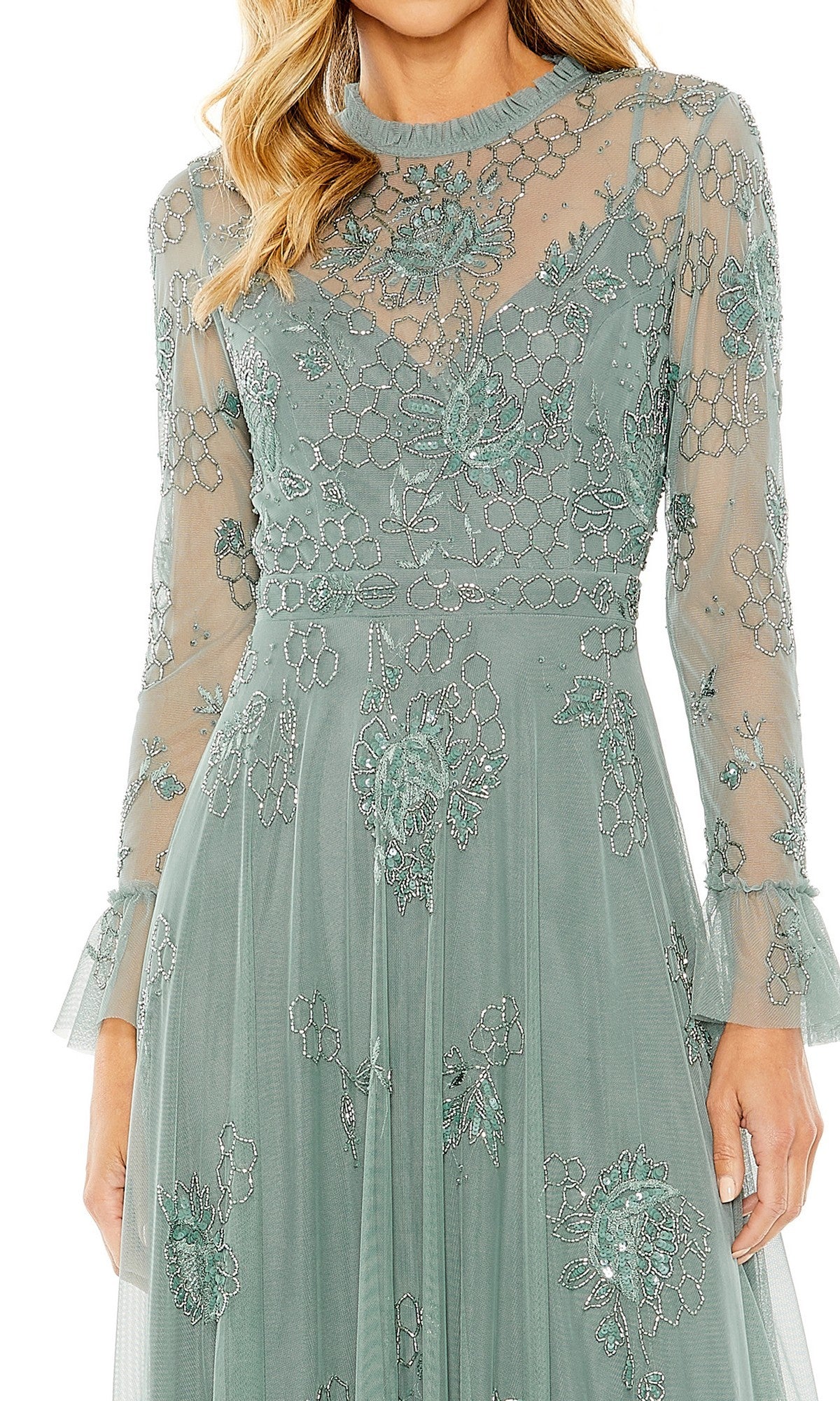 A woman wearing the Mac Duggal 9249 long formal dress in light green, adorned with beaded floral embellishments, featuring sheer long sleeves and mesh detailing at the neckline.