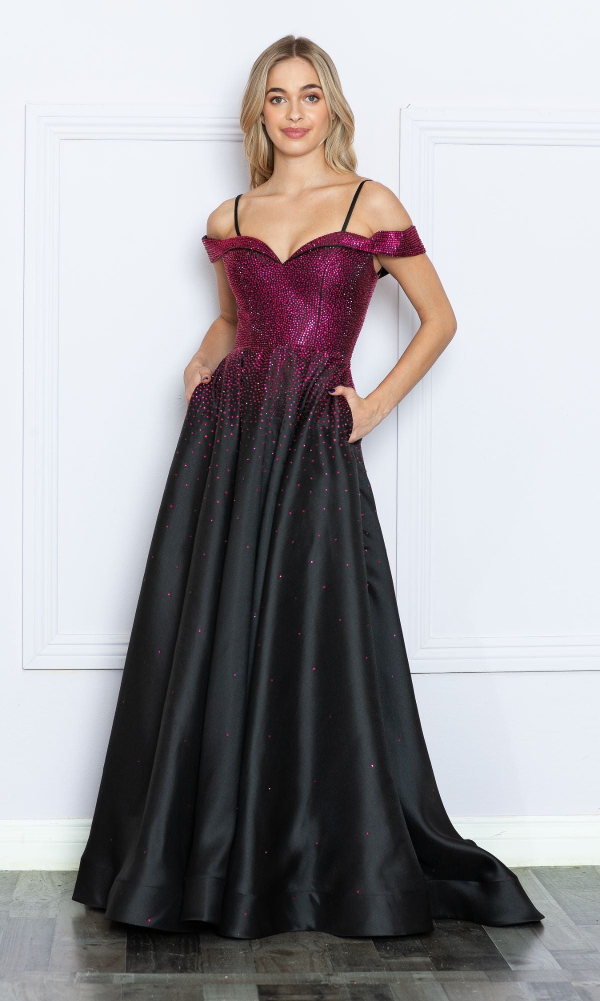 A woman stands against a white wall wearing the Cold-Shoulder Beaded Long Prom Ball Gown 9278—a long A-line dress with pink and black ombre tones, cold-shoulder detail, fitted bodice, flared skirt, and convenient pockets.