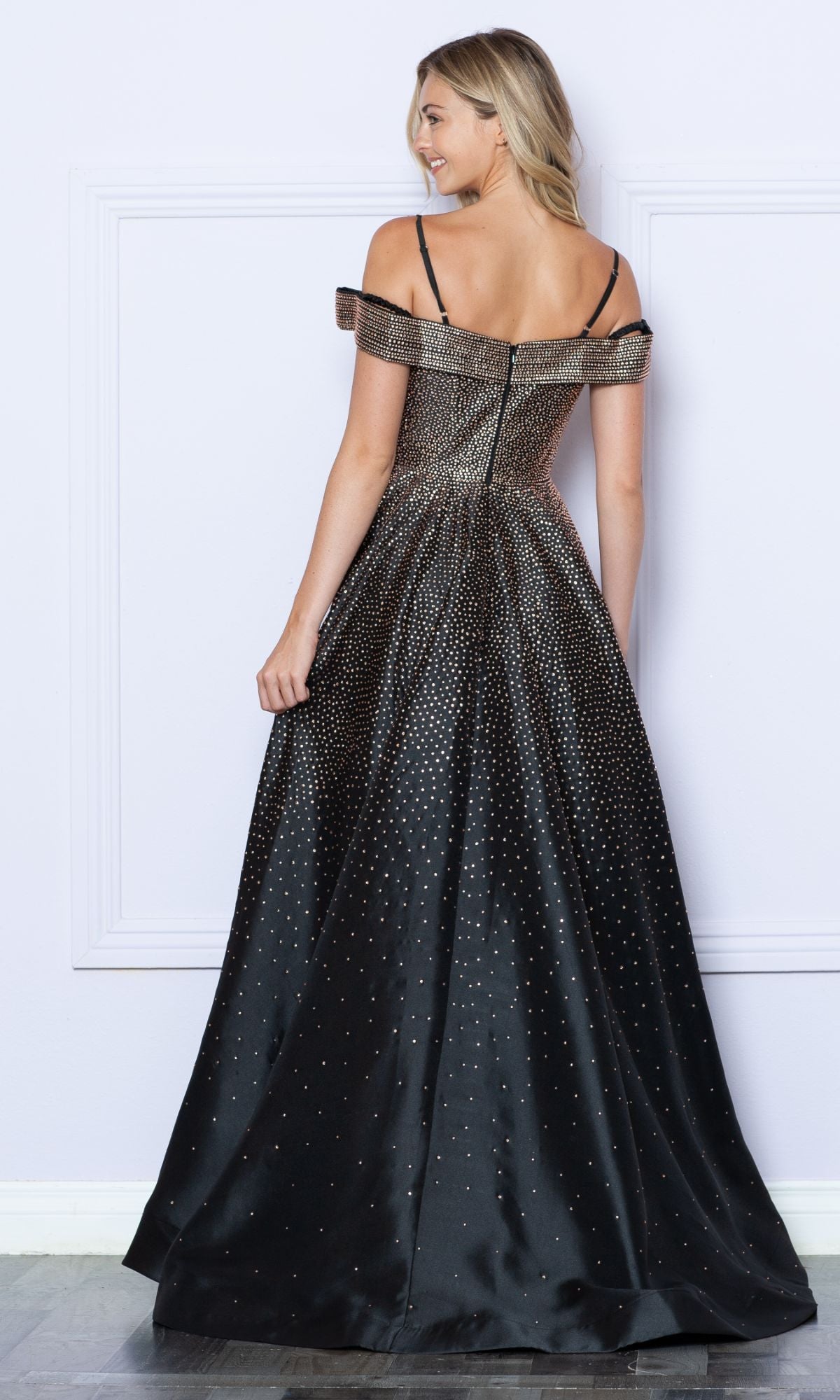 A woman faces away, wearing the Cold-Shoulder Beaded Long Prom Ball Gown 9278—an elegant black dress with sparkling embellishments, off-the-shoulder straps, and a flared skirt.
