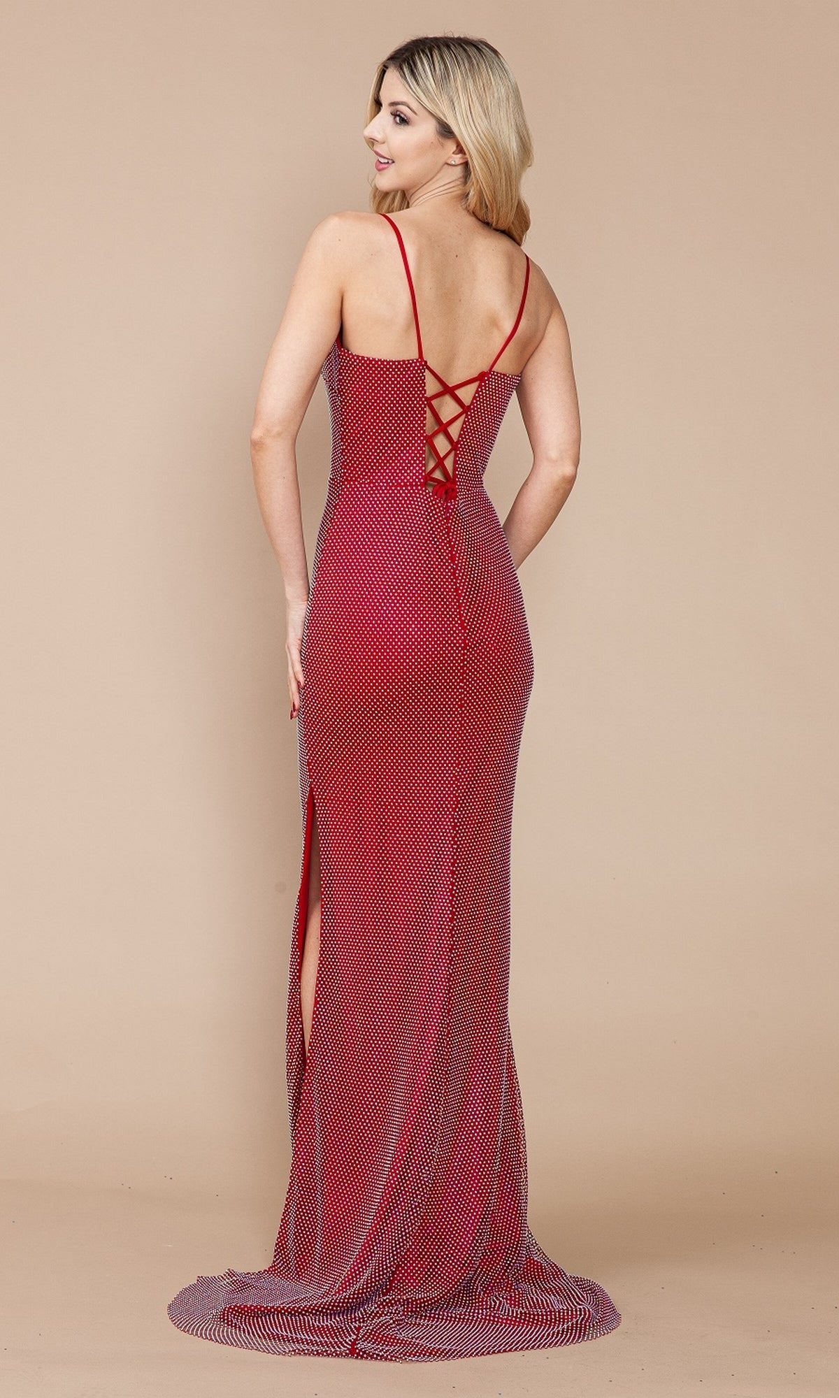 A woman faces away in the Shimmer-Net Long Lace-Up Prom Dress 9282, a floor-length red gown with thin straps, crisscross corset-back, side slit, and subtle dotted shimmer-net pattern.