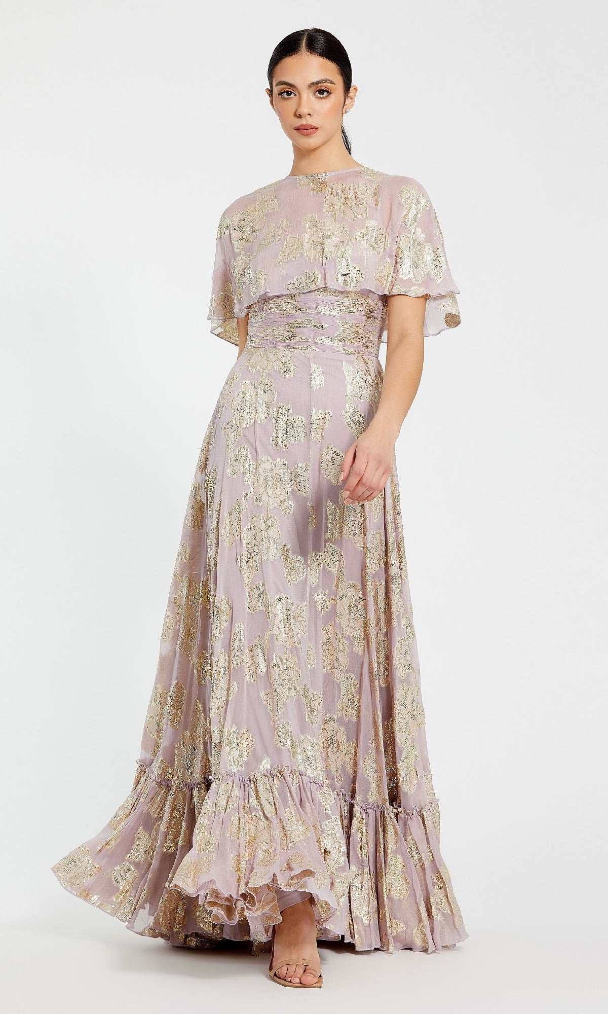 A woman stands against a plain white background wearing the Caped Long Lilac Formal Dress: Mac Duggal 9304, featuring a floor-length silhouette, ruffle hem, short cape sleeves, and paired with beige heeled sandals.