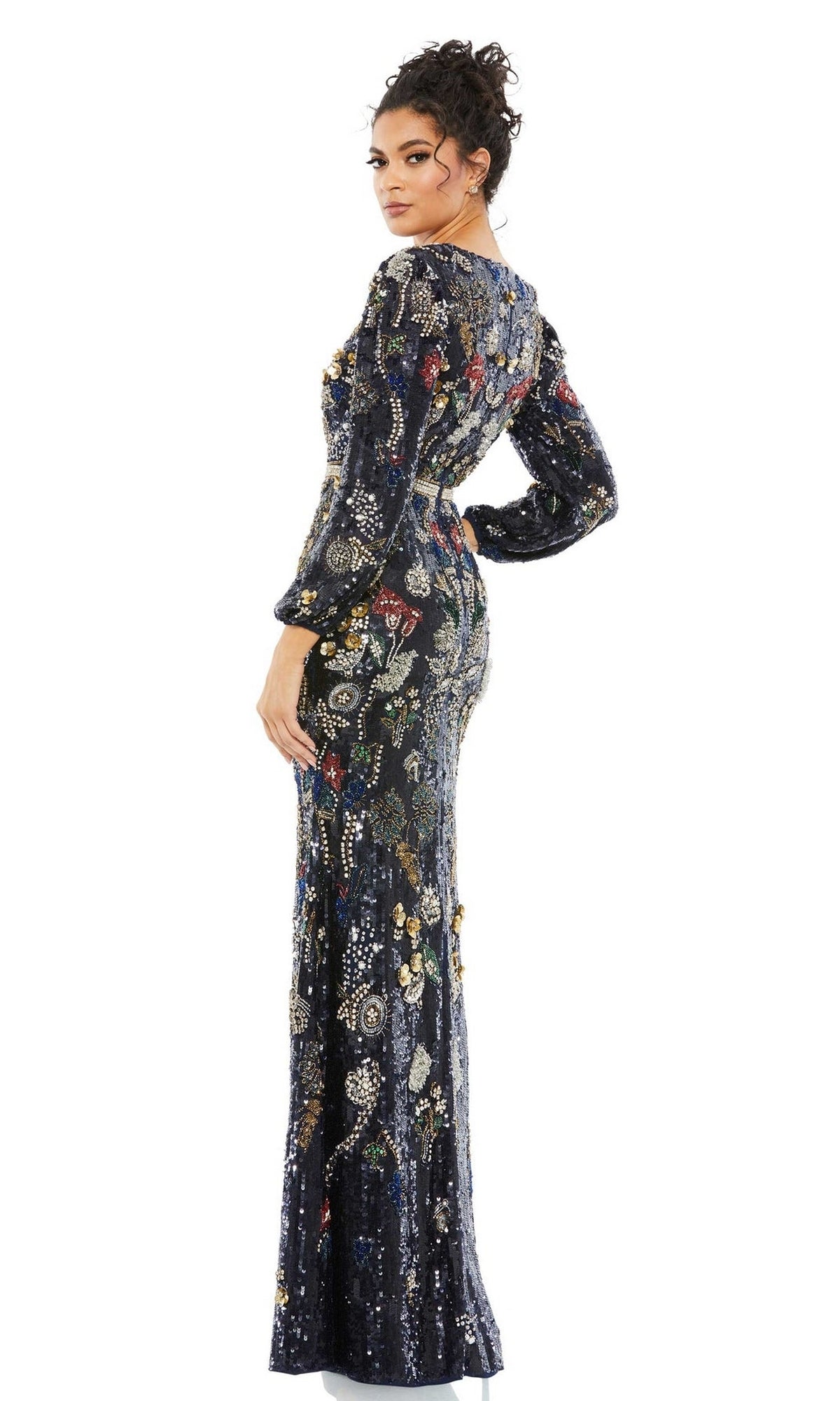 A woman poses in the Mac Duggal Long Formal Dress 93546, showcasing its v-neckline and vibrant sequin floral patterns, standing with one hand on her hip and glancing over her shoulder.