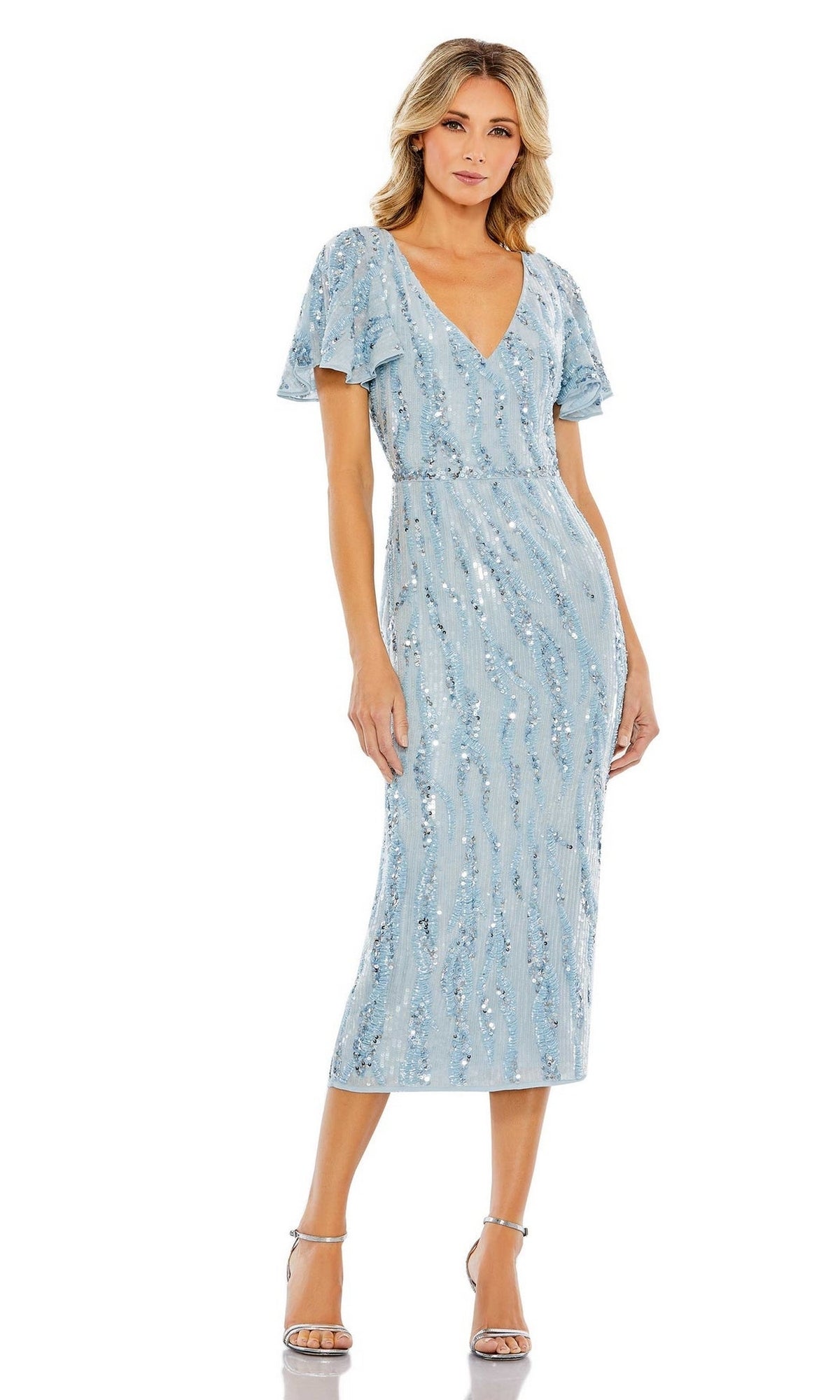 A woman wearing the Short Wedding Guest Dress 93591 by Mac Duggal, a light blue beaded midi dress with short flutter sleeves, paired with silver high-heeled sandals.