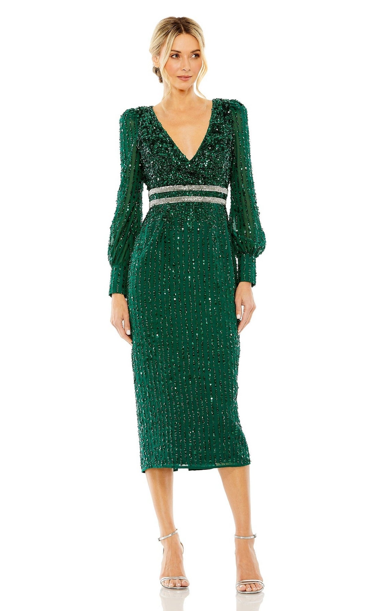 A woman in the Mac Duggal 93593 Knee-Length Wedding Guest Dress—an emerald green sequin V-neck, long-sleeve semi-formal style with a silver waistband—paired with strappy silver heels.