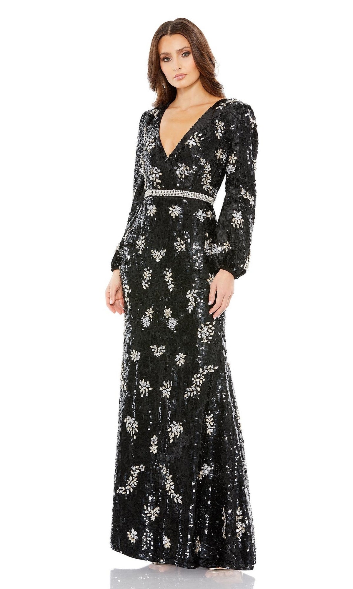 A woman models the Long Formal Dress 93616 by Mac Duggal, featuring long sleeves, a V-neckline, silver floral sequins, and a rhinestone belt, standing against a plain white background.