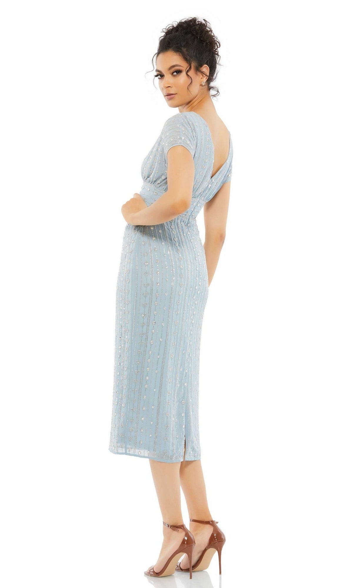 A woman poses against a plain white background wearing the Mac Duggal Beaded Short Wedding-Guest Dress 93649, featuring light blue fabric, short sleeves, vertical embellishments, an empire waist, and beige high heels.
