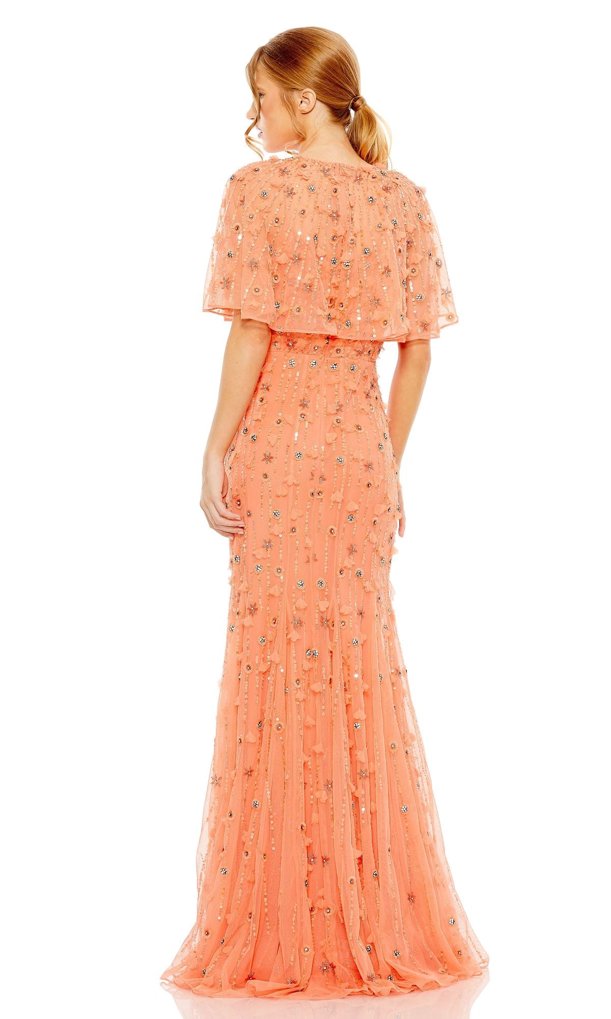 A woman faces away, wearing the Mac Duggal 93653 Beaded-Cape Long Formal Dress in peach, featuring floral embellishments and sheer cape sleeves.