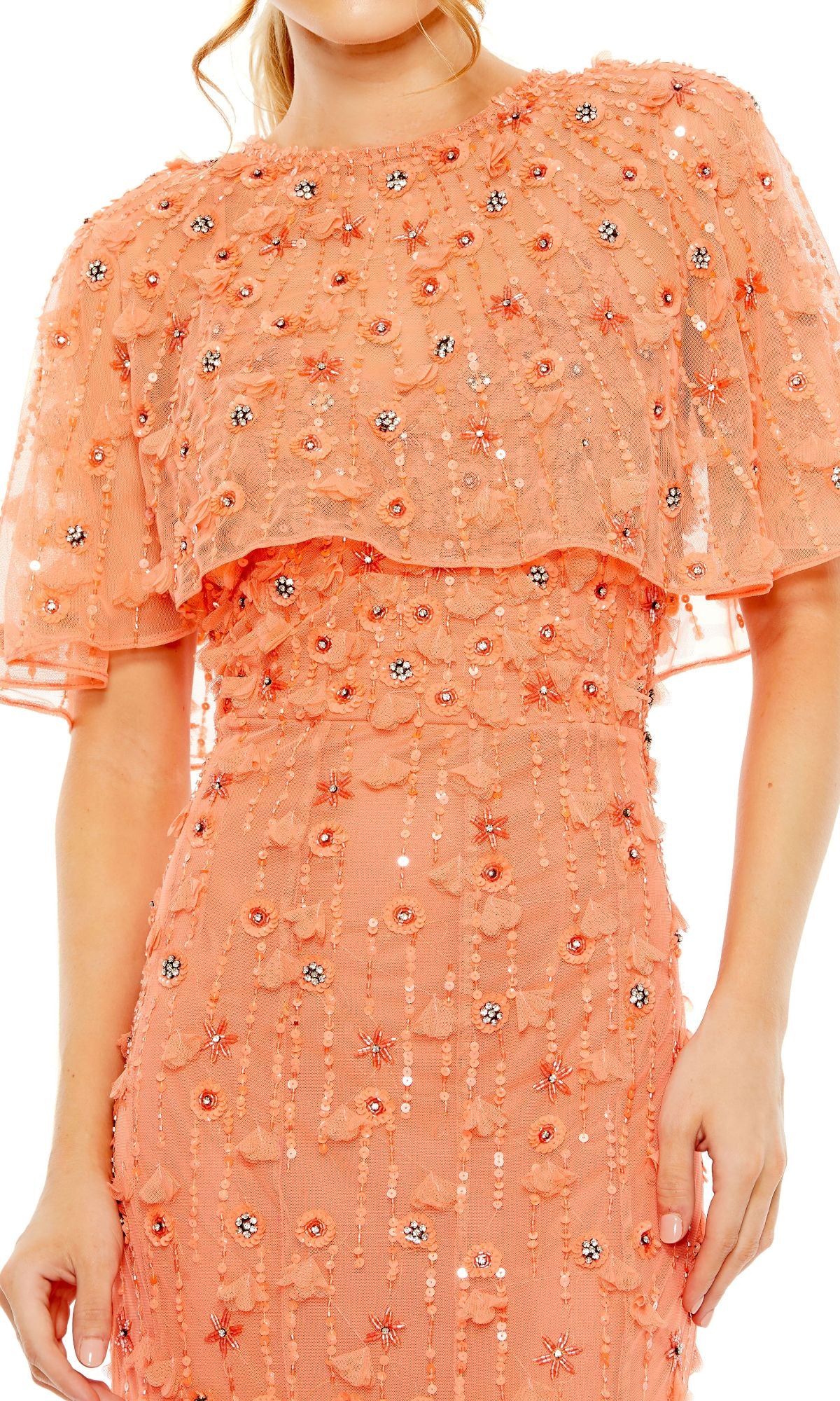 A woman wearing the Mac Duggal 93653 Beaded-Cape Long Formal Dress, featuring a peach hue, floral embroidery, and a sheer cape overlay.