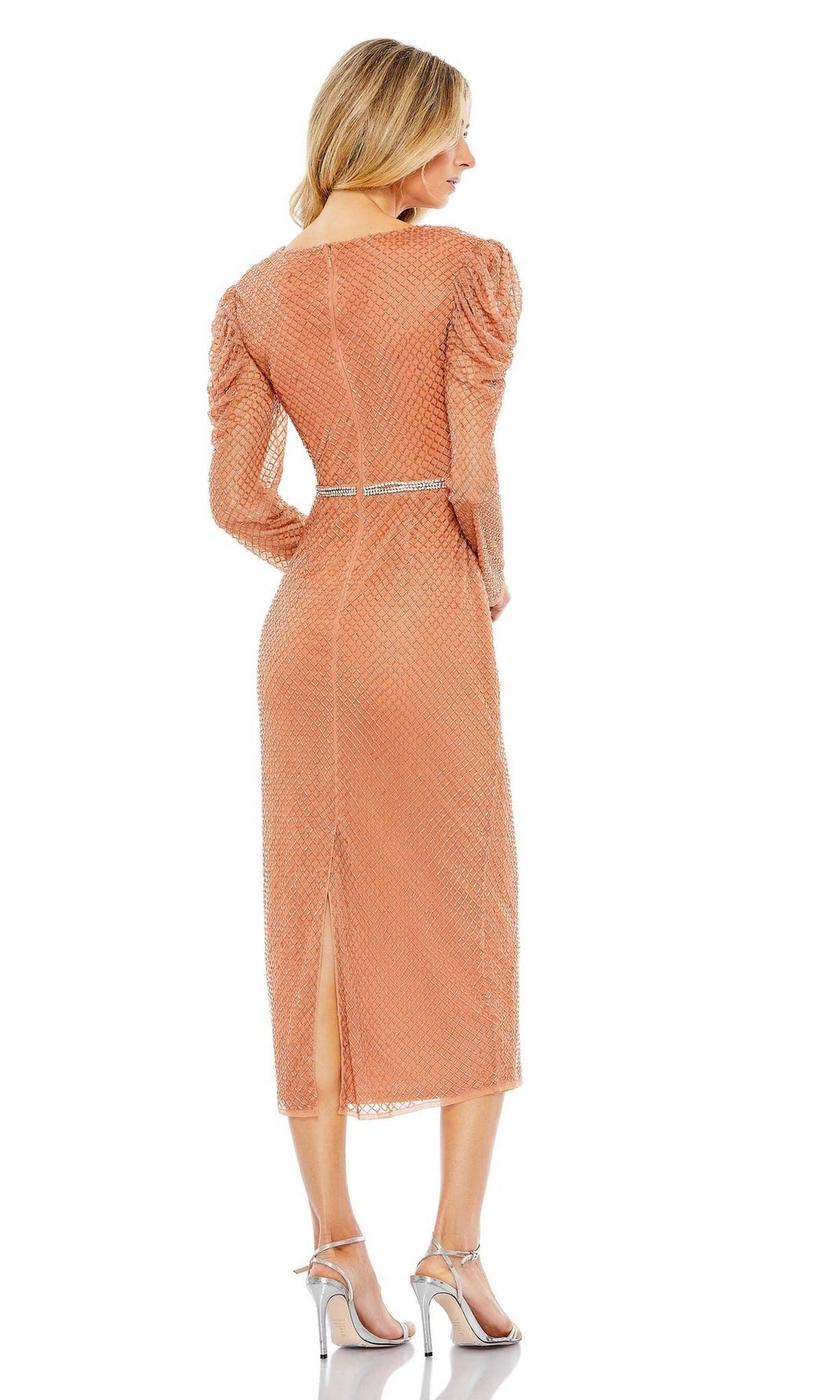 A woman wears the Short Wedding Guest Dress 93674 by Mac Duggal, a peach long-sleeve faux wrap midi dress with textured pattern, waist belt, and back slit. Paired with silver heels, it’s perfect for special occasions or semi-formal events.